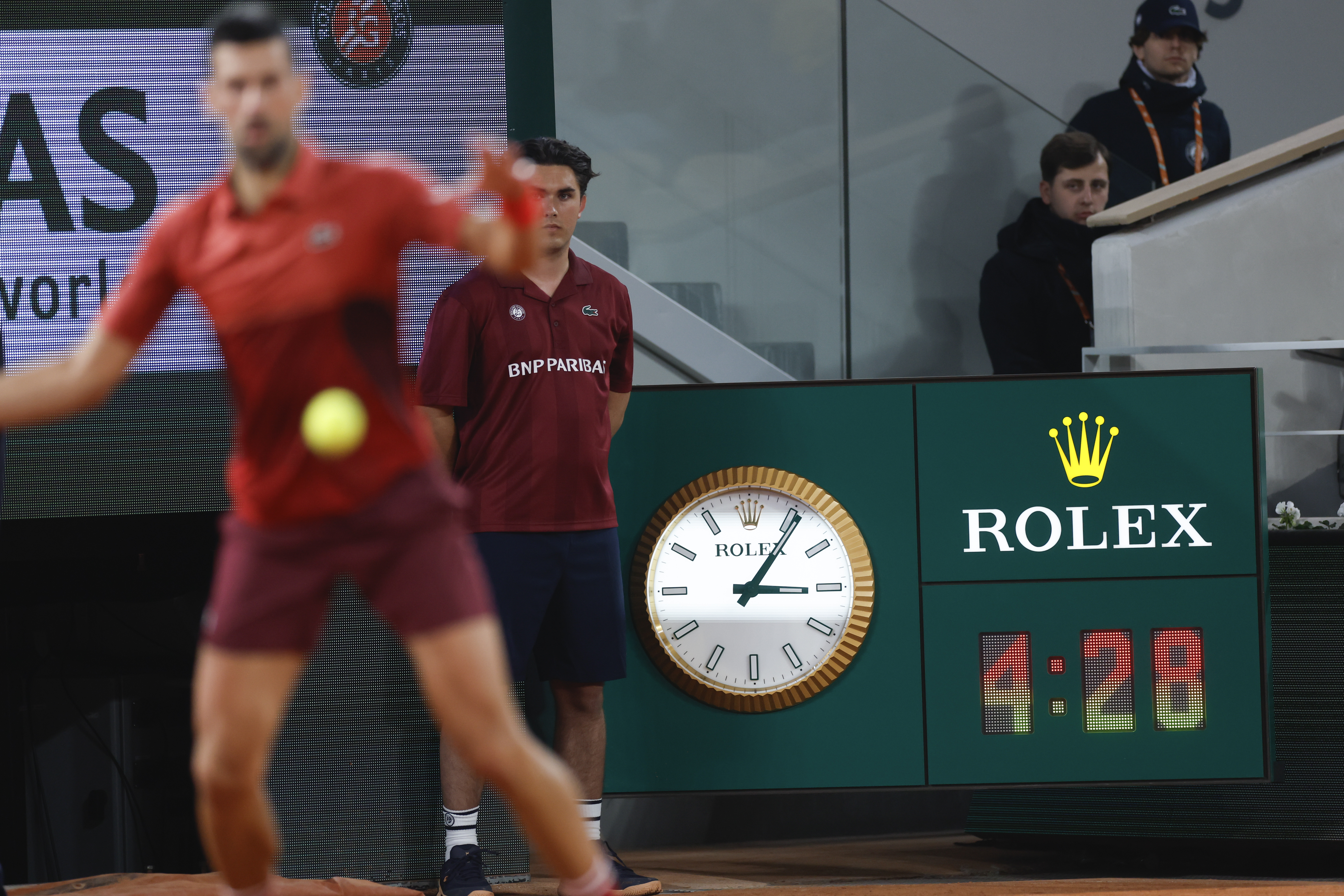 Serbia's Novak Djokovic plays a shot against Italy's Lorenzo Musetti as the clock indicates the match time played in the fifth set of their third round match of the French Open tennis tournament at the Roland Garros stadium in Paris, Sunday, June 2, 2024. 