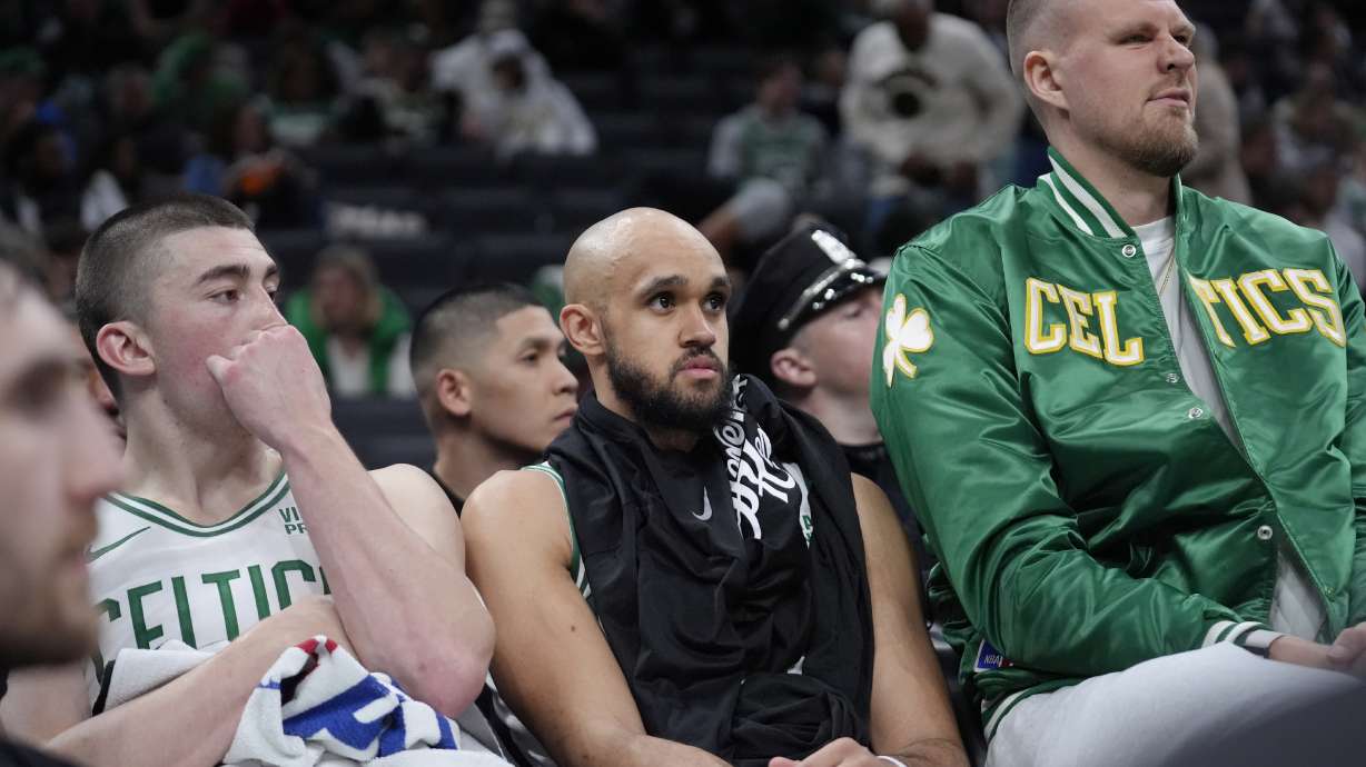 Boston Celtics guard Payton Pritchard, left, guard Derrick White, center, and center Kristaps Porzingis, right, watch from the bench as the Cleveland Cavaliers lead the Celtics during the second half of Game 2 of an NBA basketball second-round playoff series, Thursday, May 9, 2024, in Boston.