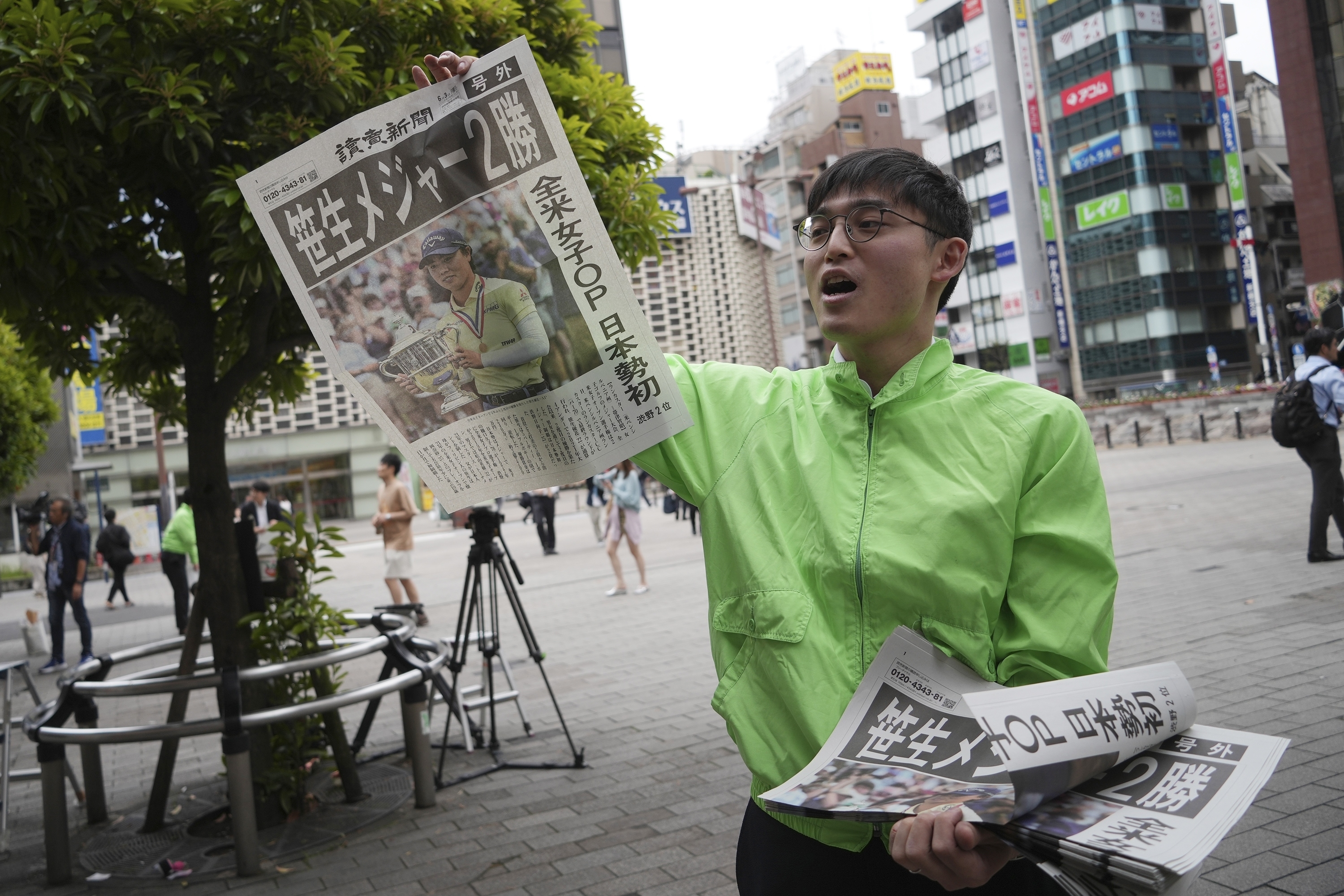 A staff distributes an extra edition of the Yomiuri Shimbun newspaper reporting on Japanese golfer Yuka Saso winning the U.S. Women's Open golf tournament Monday, June 3, 2024, in Tokyo. The Japanese title reads as "Saso won second major." 