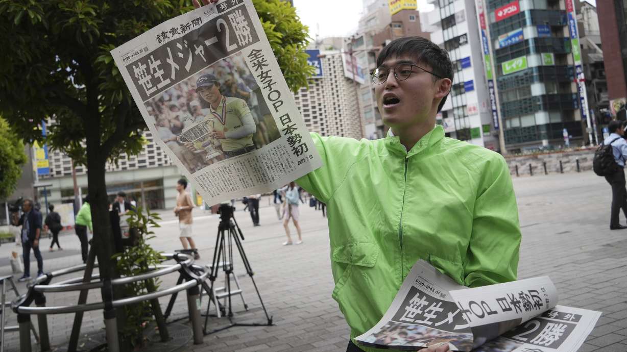 A staff distributes an extra edition of the Yomiuri Shimbun newspaper reporting on Japanese golfer Yuka Saso winning the U.S. Women's Open golf tournament Monday, June 3, 2024, in Tokyo. The Japanese title reads as "Saso won second major."