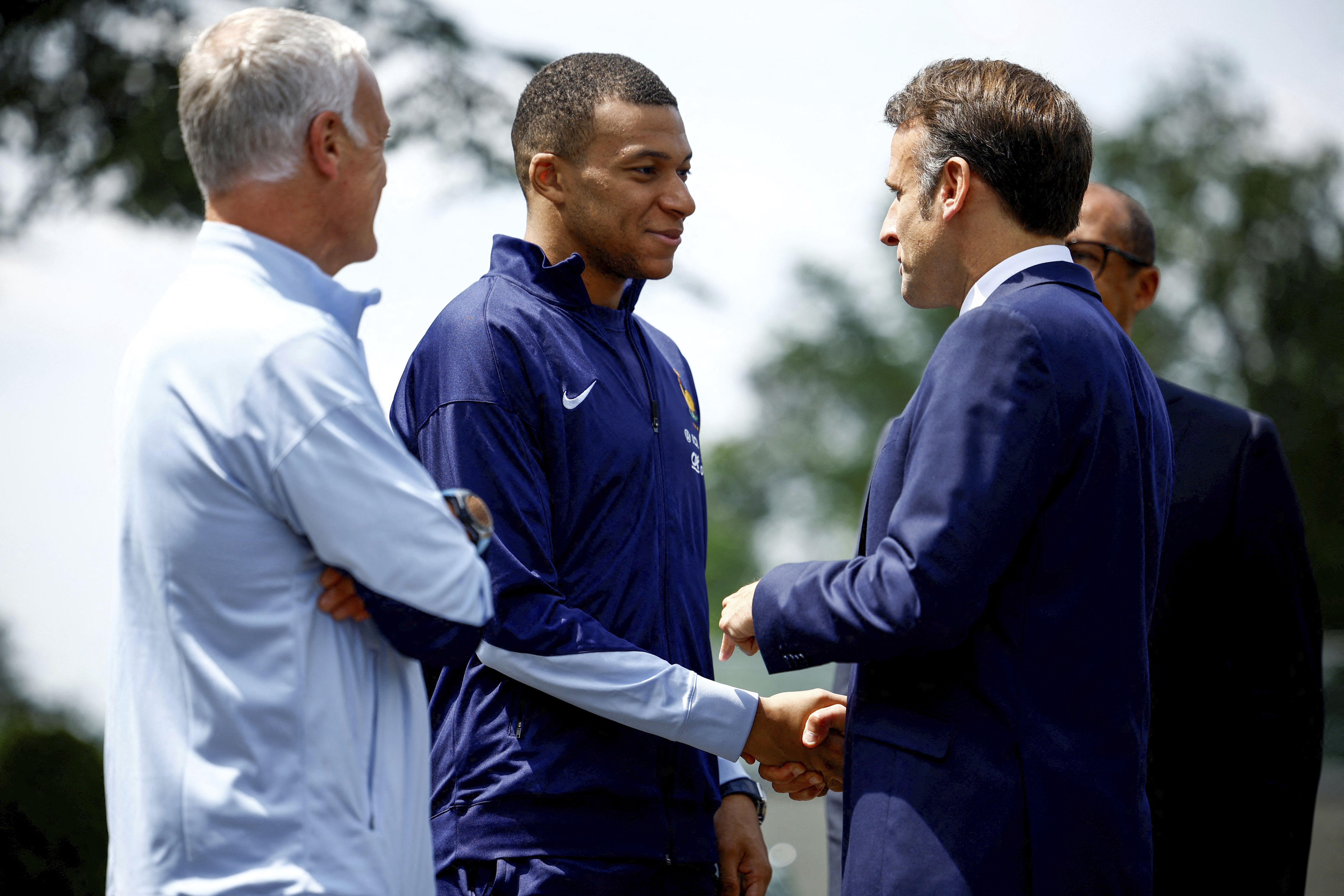 French President Emmanuel Macron, right, shakes hands with French soccer player Kylian Mbappe next to head coach Didier Deschamps as he arrives for lunch at the national soccer team training center in Clairefontaine, west of Paris, Monday, June 3, 2024 ahead of the UEFA Euro 2024. 
