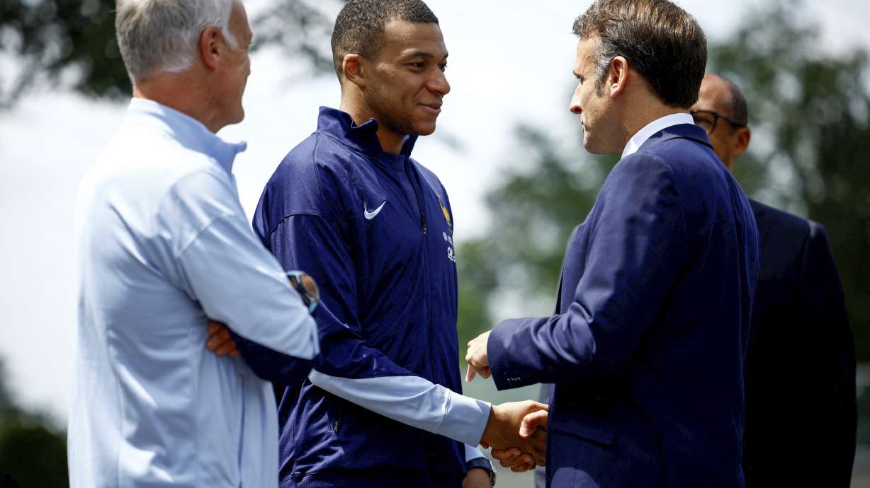 French President Emmanuel Macron, right, shakes hands with French soccer player Kylian Mbappe next to head coach Didier Deschamps as he arrives for lunch at the national soccer team training center in Clairefontaine, west of Paris, Monday, June 3, 2024 ahead of the UEFA Euro 2024.