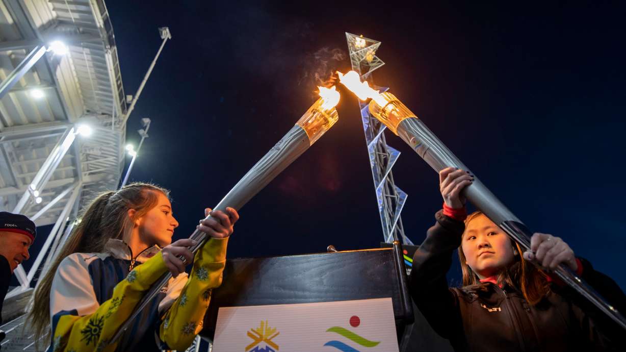 Gabrielle Harris and YiYi O’Brien combine Olympic torches from 2002 as the flame at Rice-Eccles Stadium in Salt Lake City is lit on Feb. 8, 2022. Utah was awarded the 2034 Winter Games on July 24, Pioneer Day in Utah.