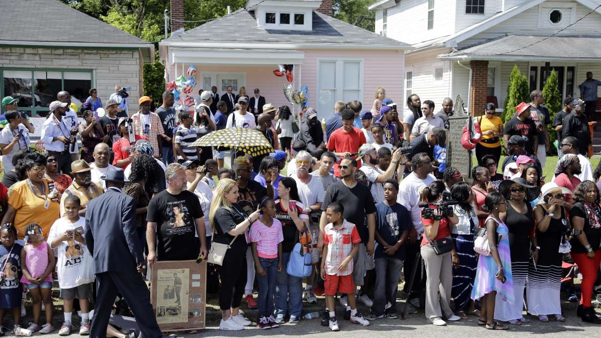 FILE - In this June 10, 2016, file photo, people line the street in front of the boyhood home, center with the pink wall, of Muhammad Ali as they wait for Ali's funeral procession to arrive in Louisville, Ky. The house where Ali grew up dreaming of boxing fame is up for sale. The house was converted into a museum offering a glimpse into the boxing great's formative years. It went on the market Tuesday, June 4, 2024 along with two neighboring homes.