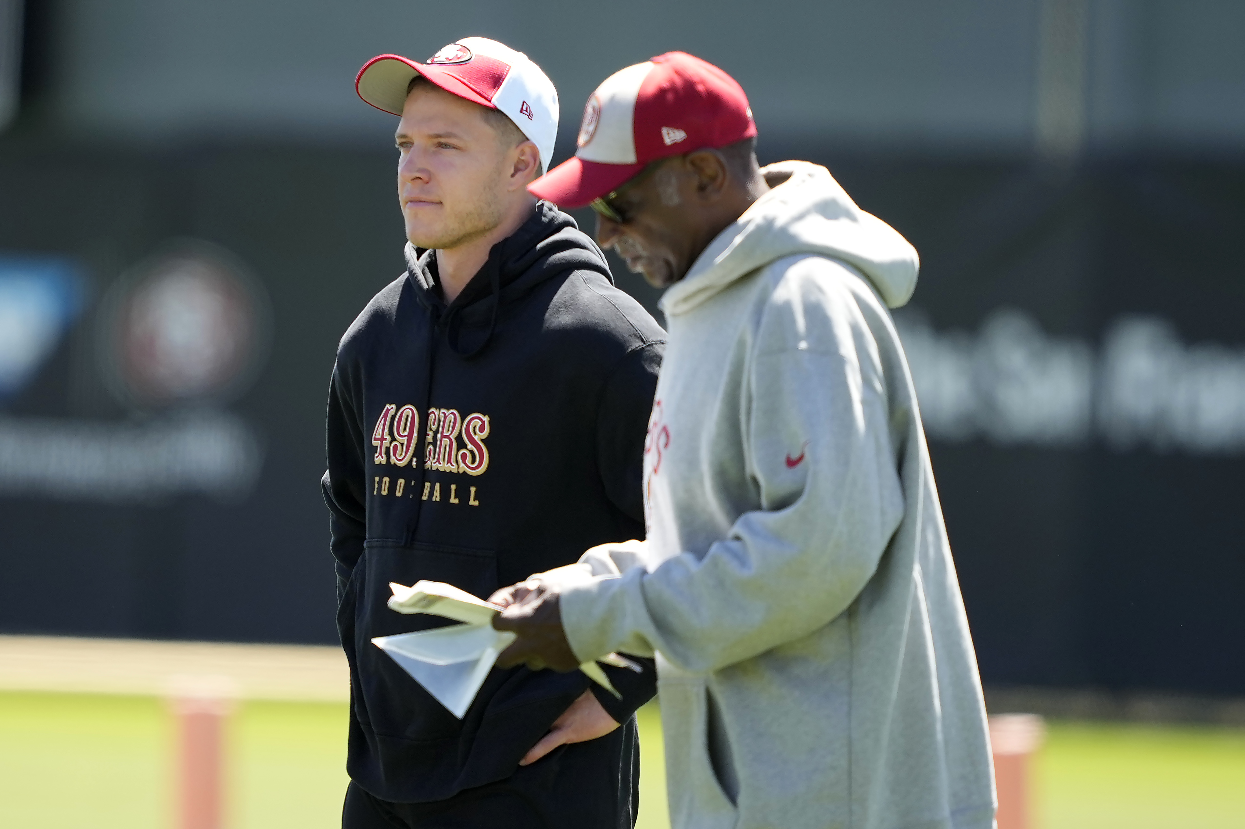 San Francisco 49ers running back Christian McCaffrey, left, watches drills with running back coach Robert Turner Jr., right, during NFL football practice in Santa Clara, Calif., Tuesday, June 4, 2024. 