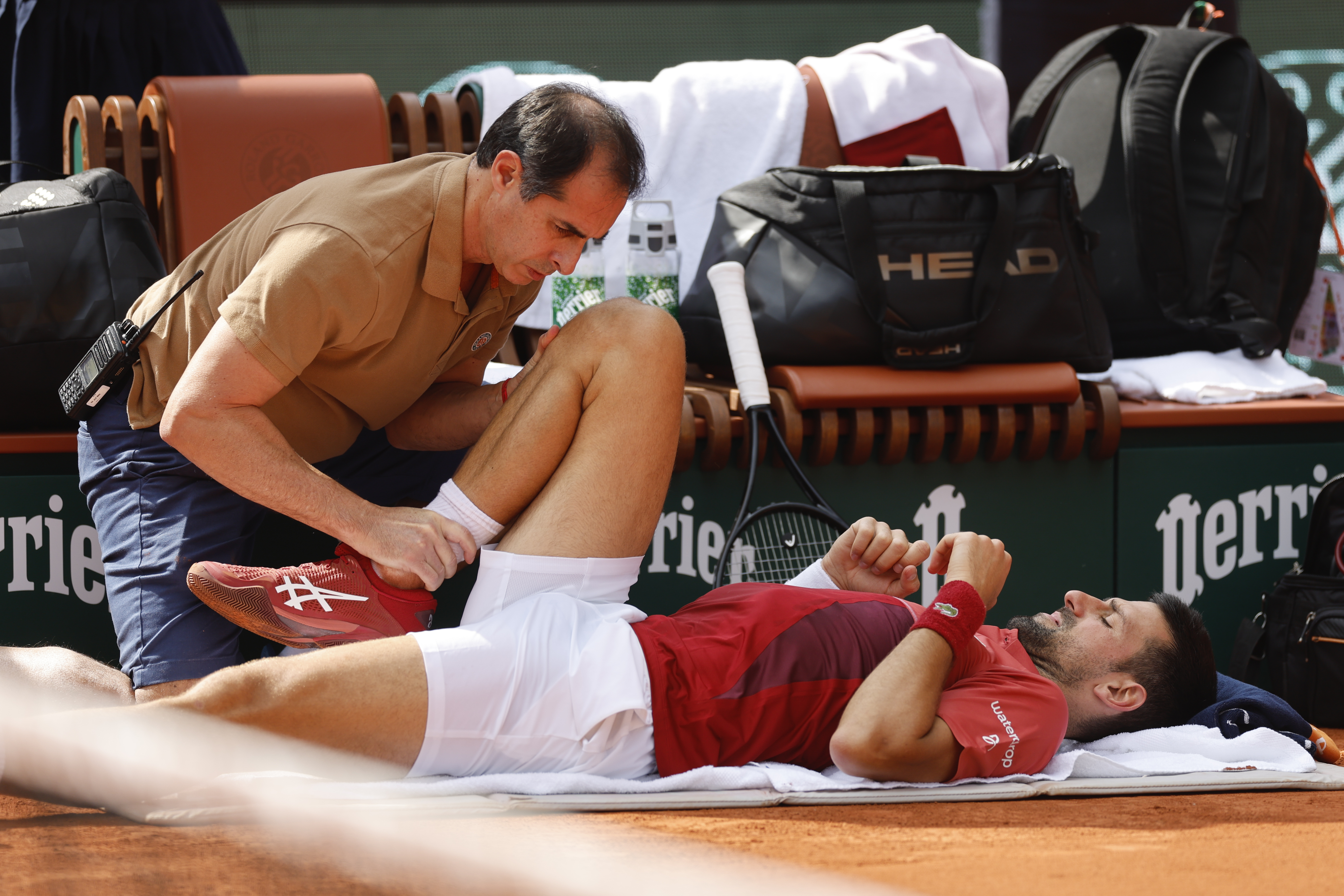 FILE - Serbia's Novak Djokovic receives medical assistance for his right knee during his fourth round match of the French Open tennis tournament against Argentina's Francisco Cerundolo at the Roland Garros stadium in Paris, Monday, June 3, 2024. Novak Djokovic withdrew from the French Open with an injured right knee on Tuesday, June 4, 2024, ending his title defense and meaning he will relinquish the No. 1 ranking. 
