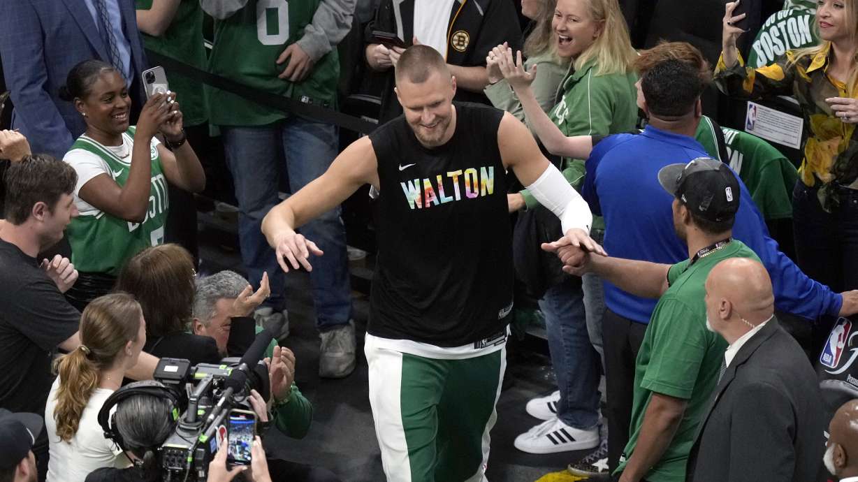 Boston Celtics center Kristaps Porzingis heads to the court while wearing a warmup shirt honoring basketball great Bill Walton before Game 1 of the basketball team's NBA Finals against the Dallas Mavericks, Thursday, June 6, 2024, in Boston.