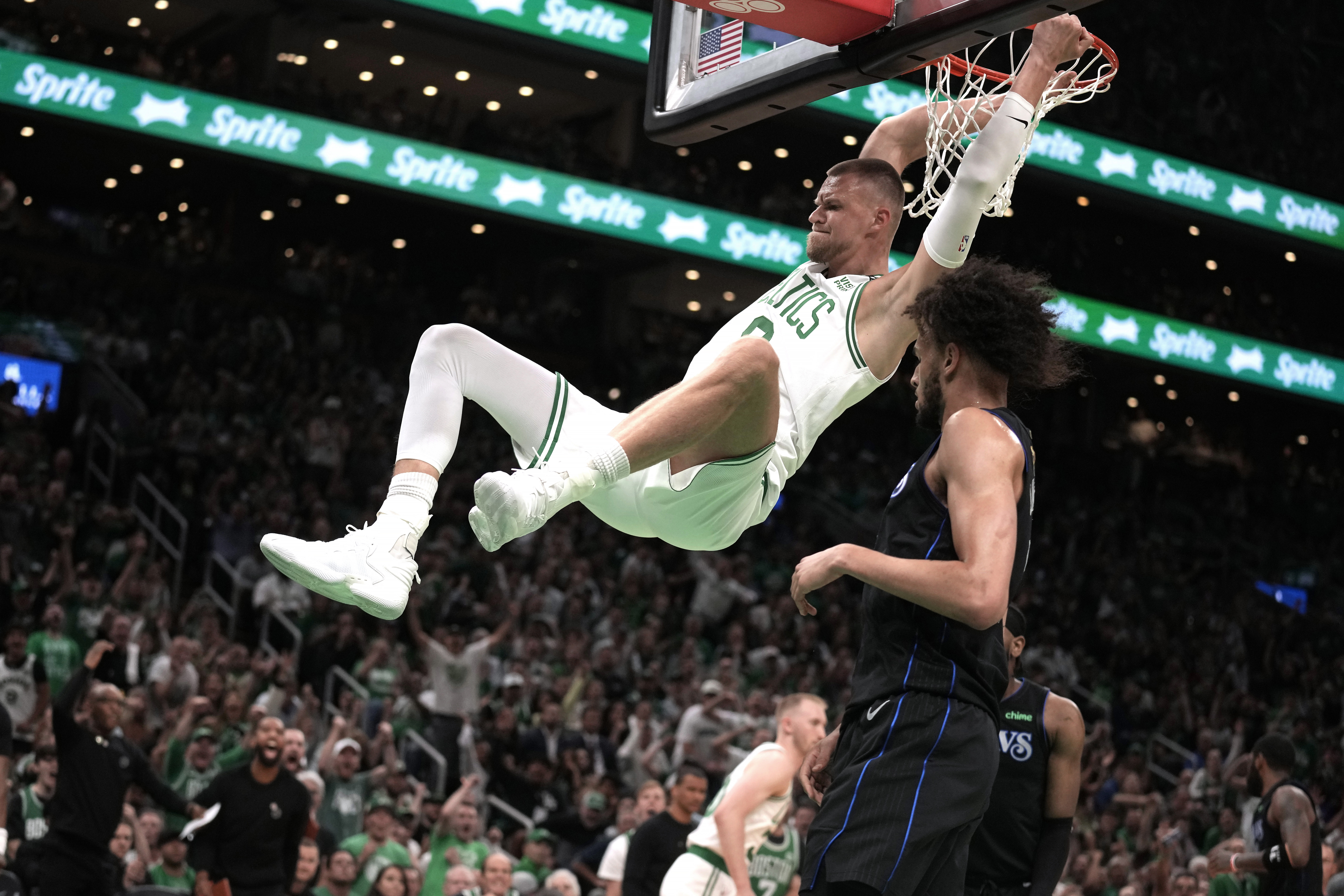 Boston Celtics center Kristaps Porzingis dunks next to Dallas Mavericks center Dereck Lively II, foreground, during the first half of Game 1 of basketball's NBA Finals on Thursday, June 6, 2024, in Boston. 