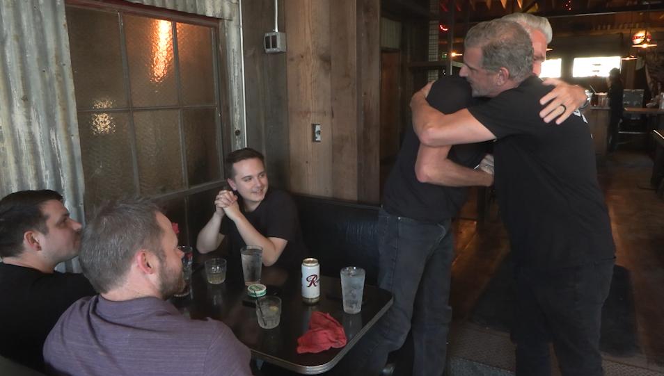 Garage on Beck owner Bob McCarthy, right, hugs a customer who returned for the reopening Thursday.