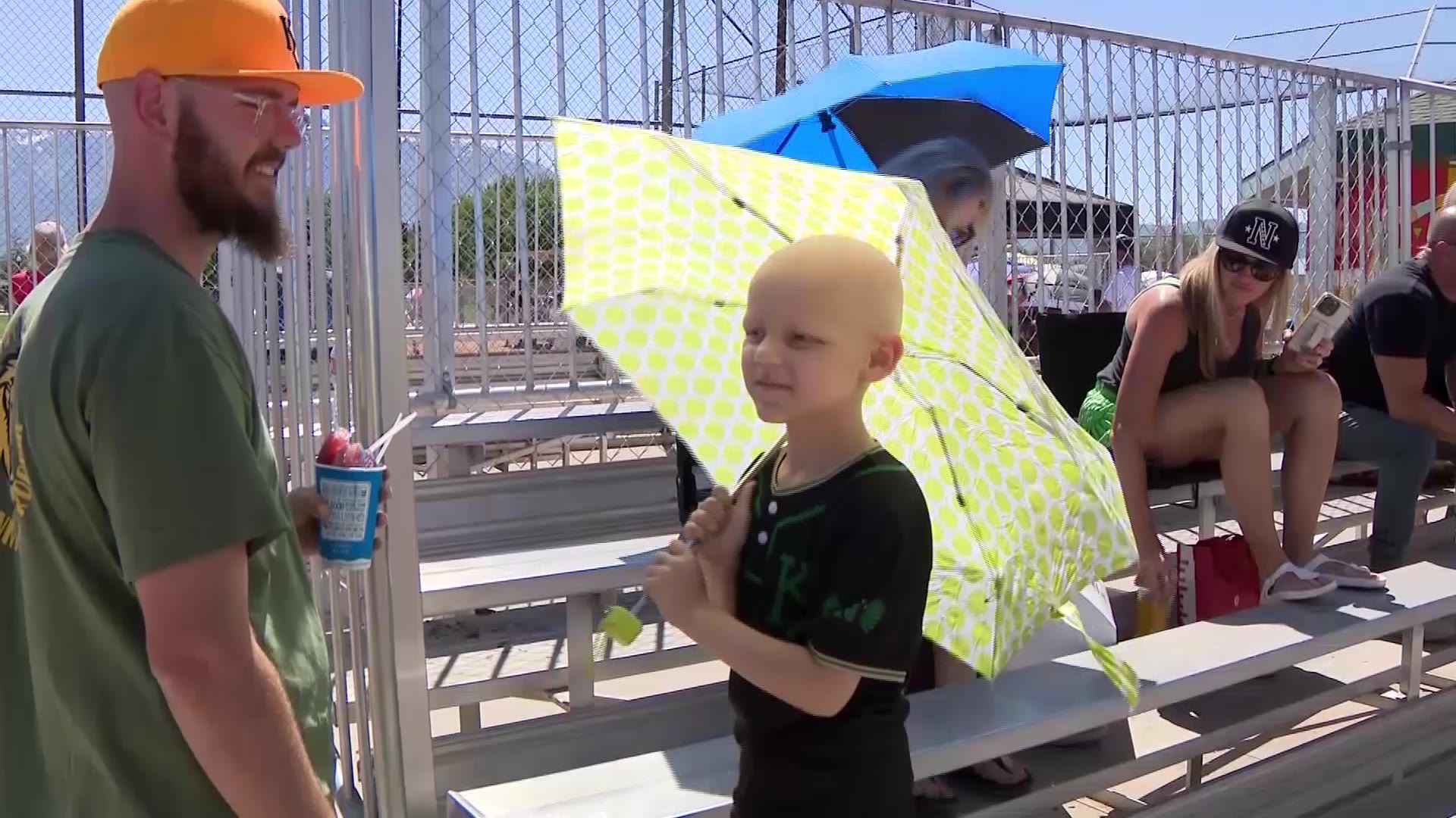 Paxton wears his team uniform and holds an umbrella. He is also battling against cancer after a 2023 diagnosis.