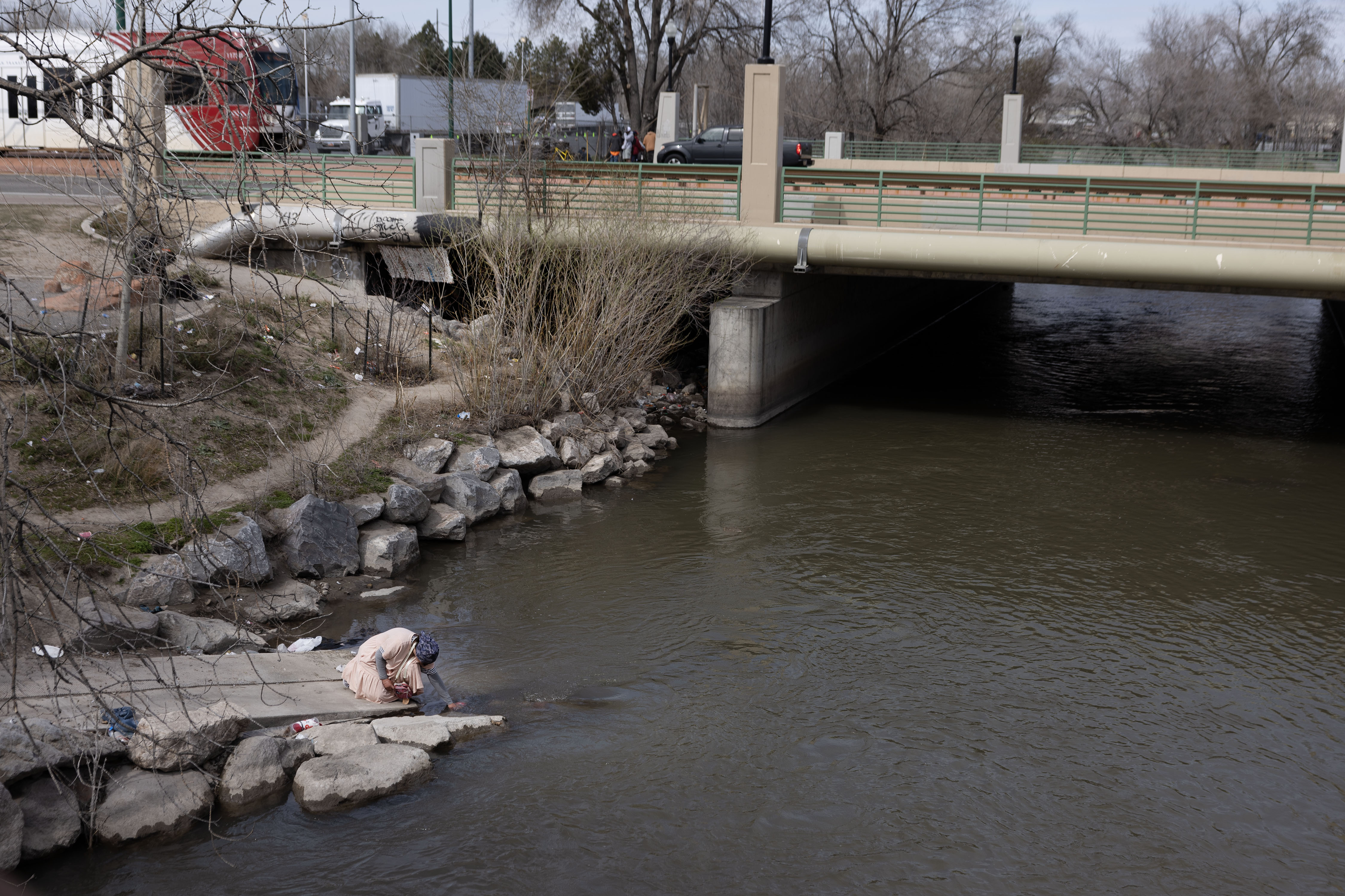 A homeless woman washes her face after filling an empty Coke bottle with water from the Jordan River in Salt Lake City on March 22. Salt Lake City leaders say they plan to direct funds to create more public bathrooms and also study the Jordan River.