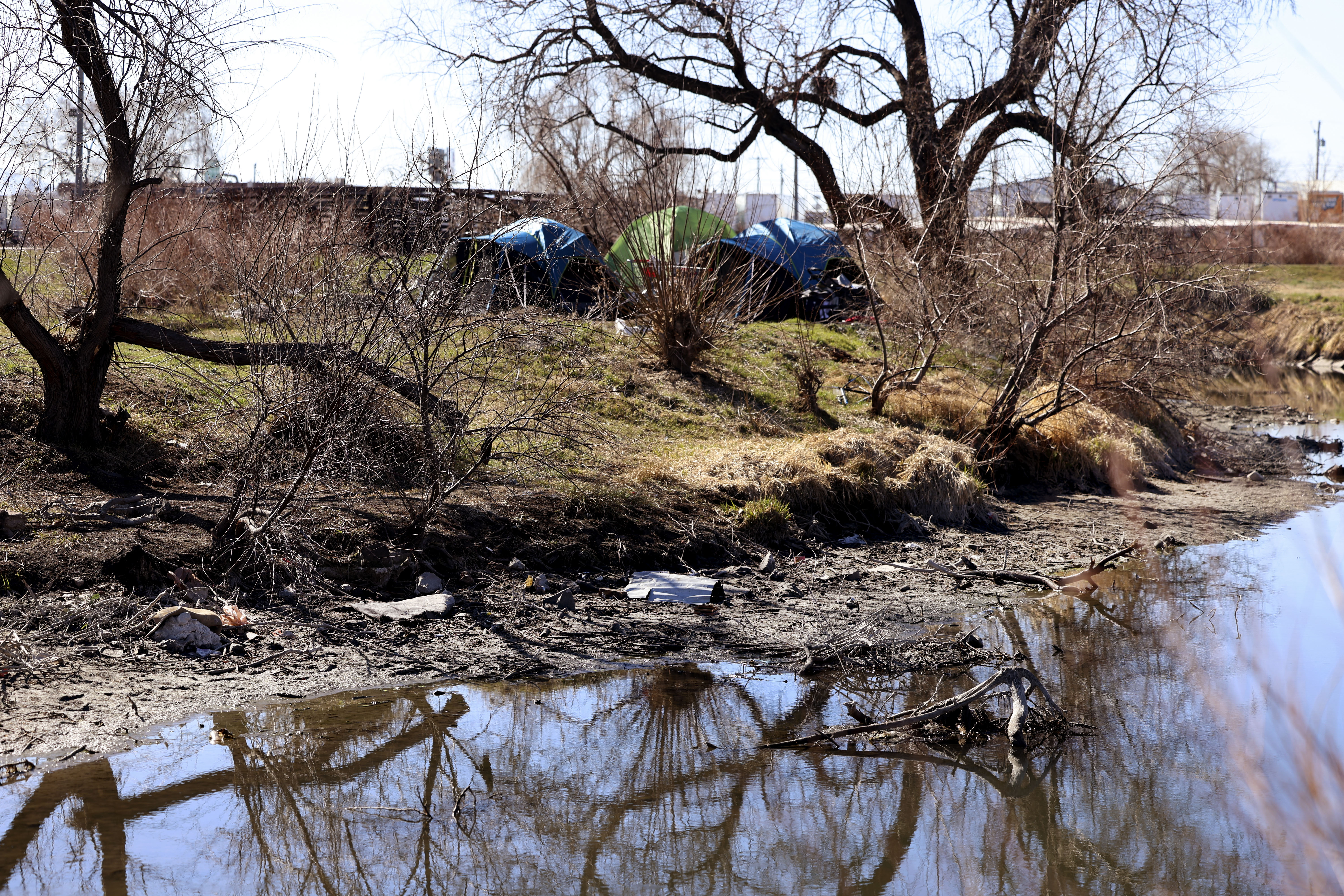 Garbage is visible near a homeless encampment on the bank of the Jordan River at a homeless encampment in Salt Lake City on March 23, 2022.