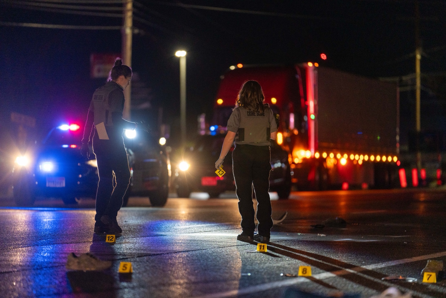 Two Salt Lake City Police Crime Lab technicians place evidence markers on Redwood Road near 1040 South after a car going north hit a man crossing the street on Saturday.
