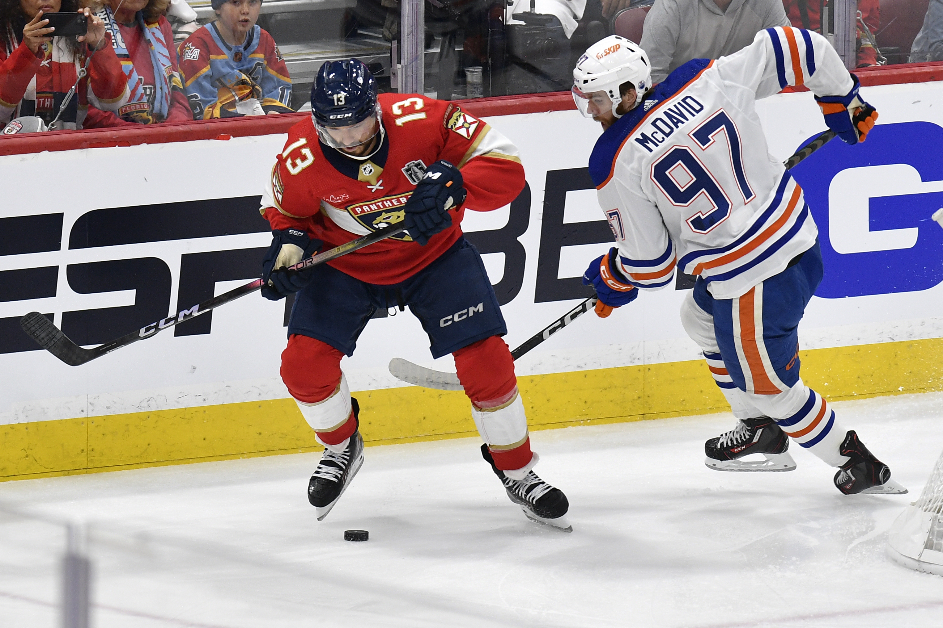 Florida Panthers center Sam Reinhart (13) and Edmonton Oilers center Connor McDavid (97) go for the puck during the first period of Game 1 of the NHL hockey Stanley Cup Finals, Saturday, June 8, 2024, in Sunrise, Fla. 