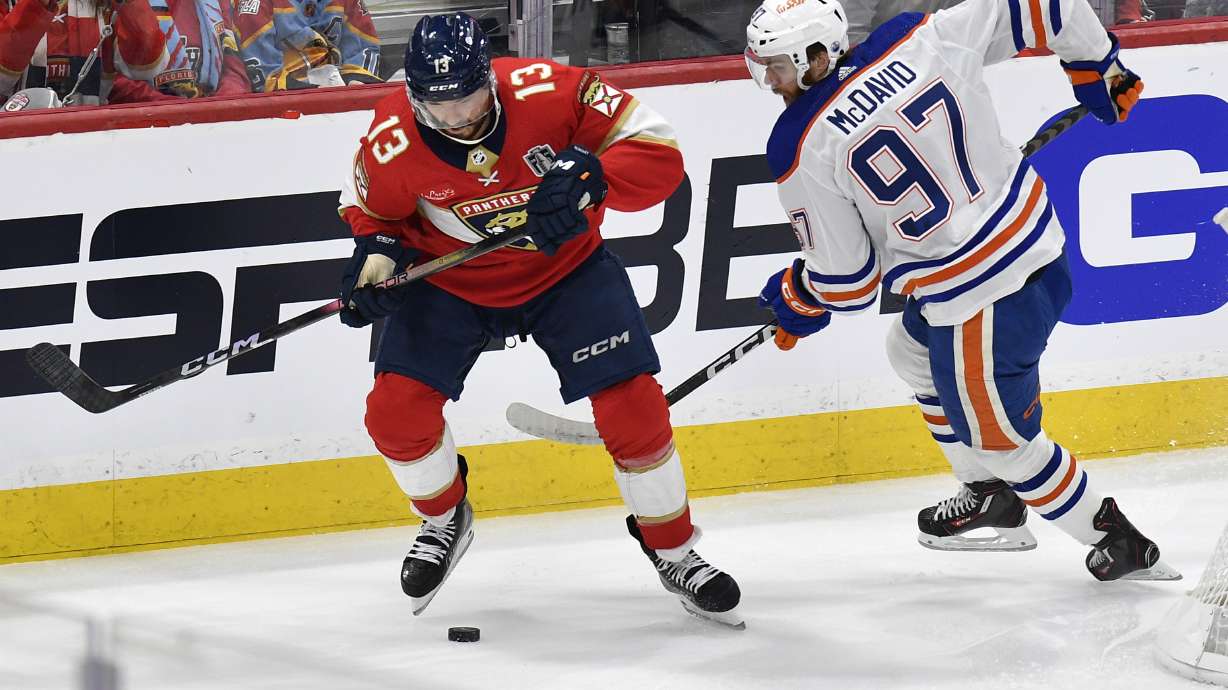 Florida Panthers center Sam Reinhart (13) and Edmonton Oilers center Connor McDavid (97) go for the puck during the first period of Game 1 of the NHL hockey Stanley Cup Finals, Saturday, June 8, 2024, in Sunrise, Fla.