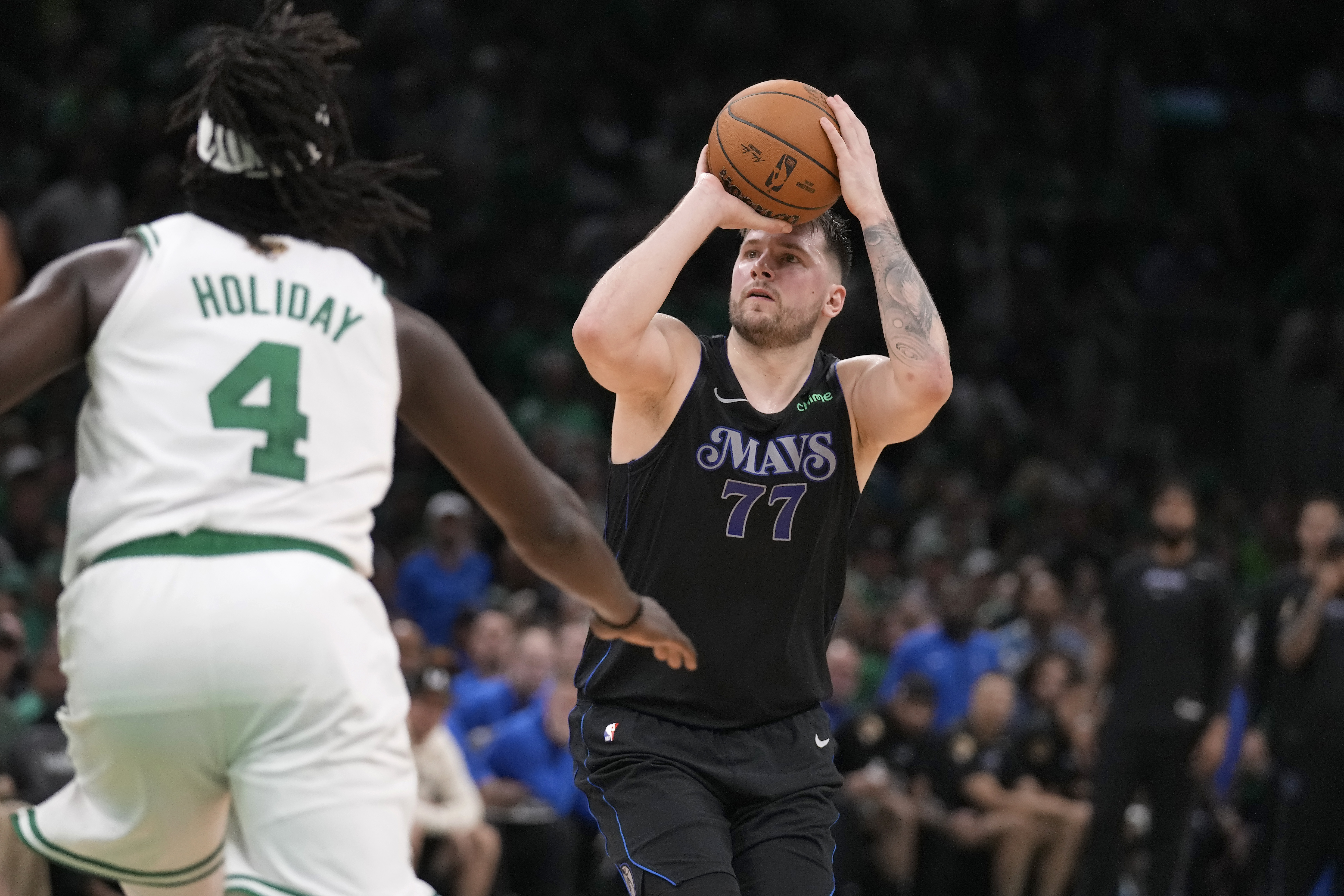 Dallas Mavericks guard Luka Doncic (77) shoots and misses a three-point attempt as Boston Celtics guard Jrue Holiday (4) defends during the second half of Game 1 of the NBA Basketball Finals, Thursday, June 6, 2024, in Boston. 