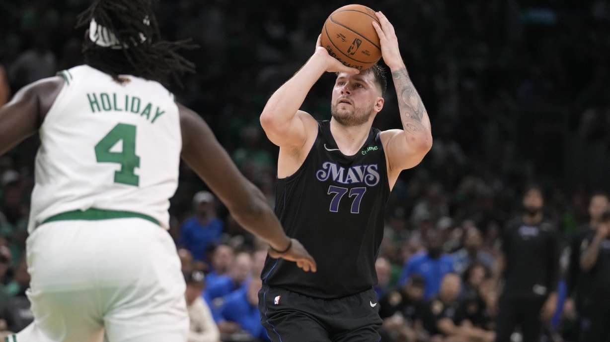 Dallas Mavericks guard Luka Doncic (77) shoots and misses a three-point attempt as Boston Celtics guard Jrue Holiday (4) defends during the second half of Game 1 of the NBA Basketball Finals, Thursday, June 6, 2024, in Boston.