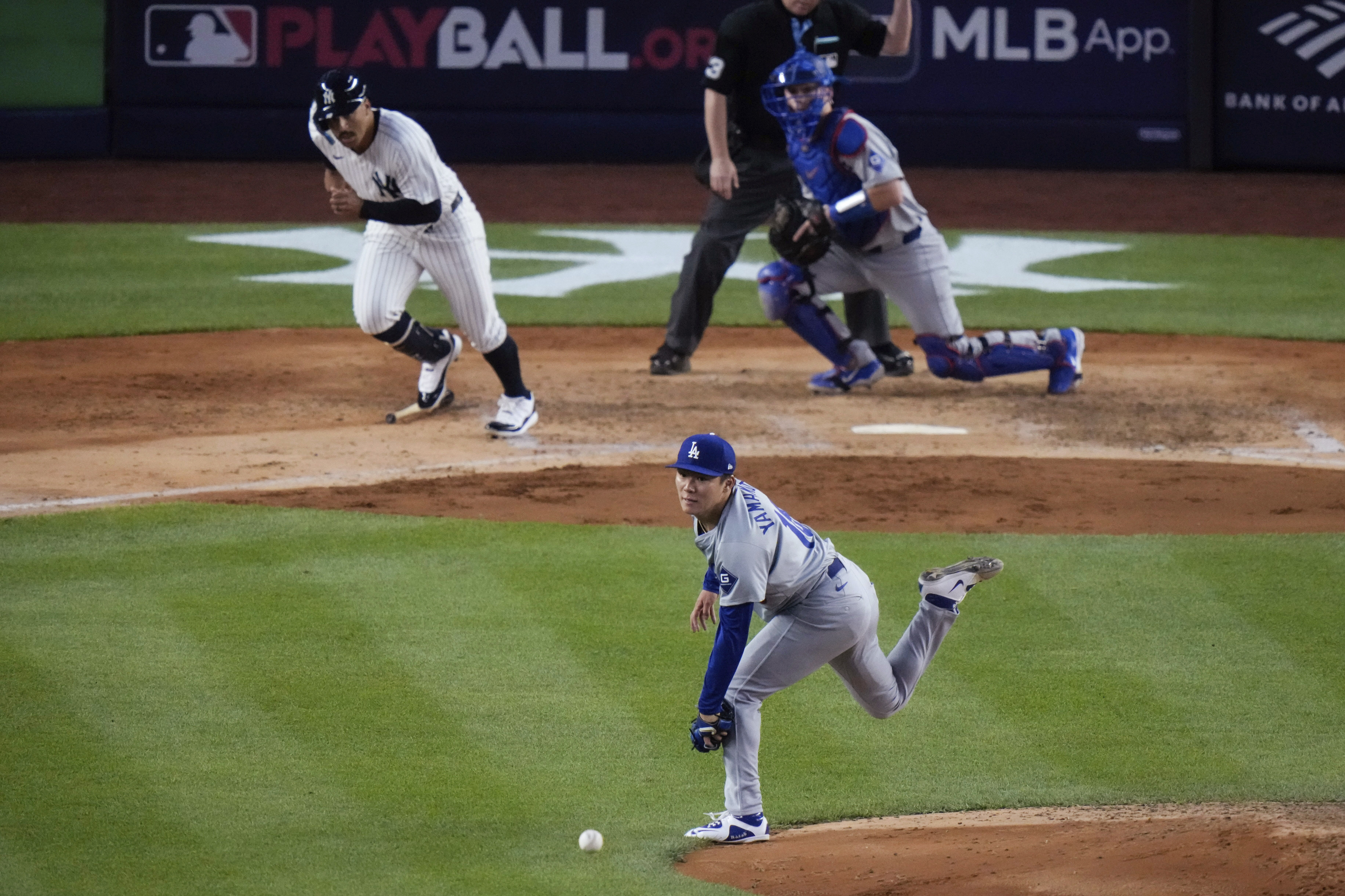 Los Angeles Dodgers pitcher Yoshinobu Yamamoto reaches for a ball hit by New York Yankees' Trent Grisham during the fifth inning of a baseball game, Friday, June 7, 2024, in New York. Grisham was out on the play. The Dodgers won 2-1 in 11 innings.