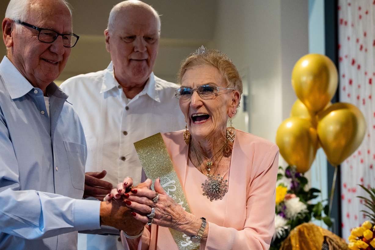 Georgia Presnell, joined by her sons Burt Presnell, left, and Greg Presnell, smiles after blowing out the candles as she celebrates her 105th birthday with family and friends at Treeo, a senior living center, in Orem on Friday.