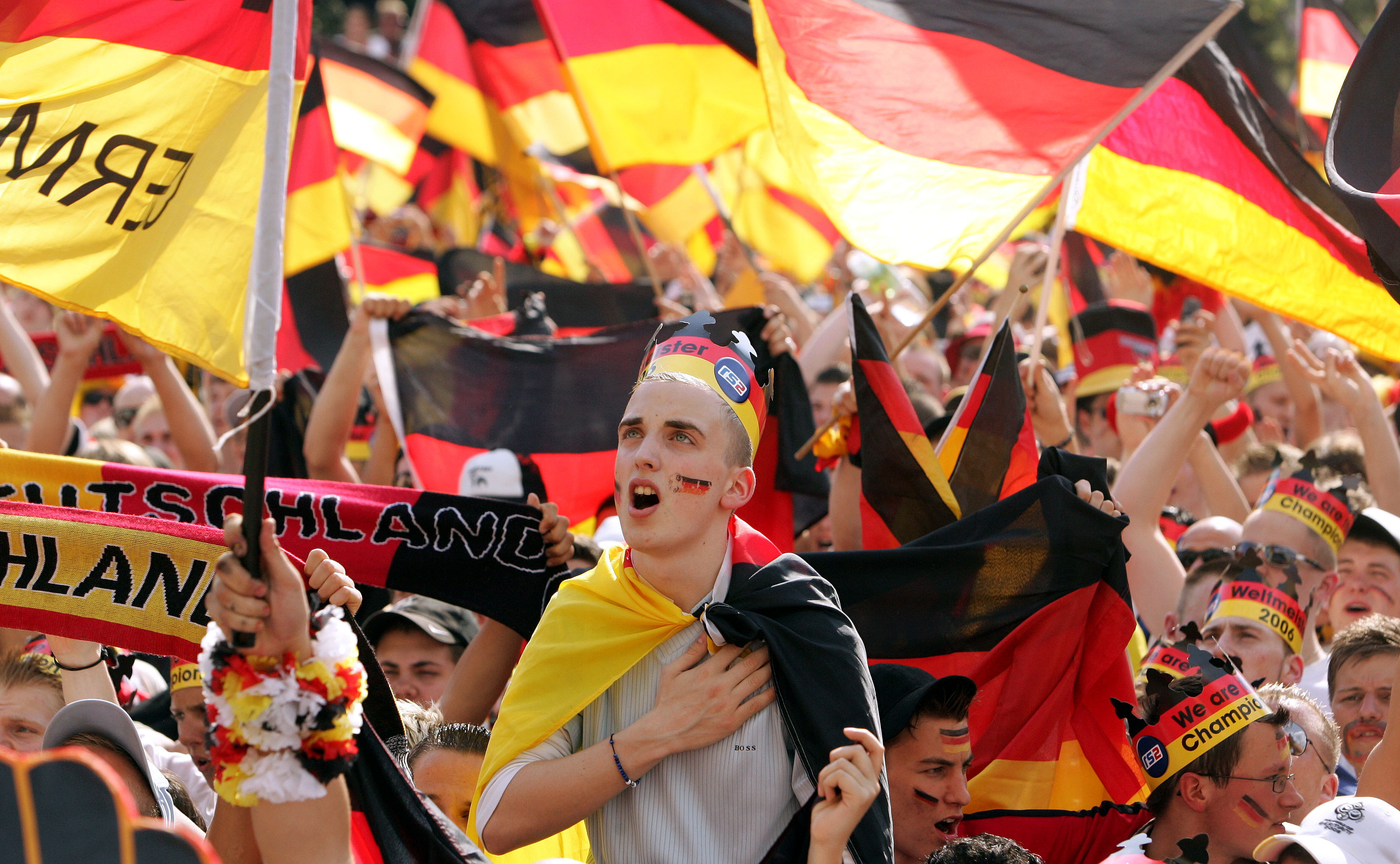 FILE - A German soccer fan sings the German national anthem prior to the beginning of the Round of 16 of the World Cup soccer match Germany against Sweden at the public viewing area where fans could watch the match live from Munich, on a giant television screen in Berlin, Saturday, June 24, 2006. Germany gets the 2024 European Championship underway against Scotland in Munich on Friday. However, away from the stadiums and public-viewing areas, few German flags are flying. Germany's dark history, rising far-right cast shadow on national pride before it hosts Euro 2024. 