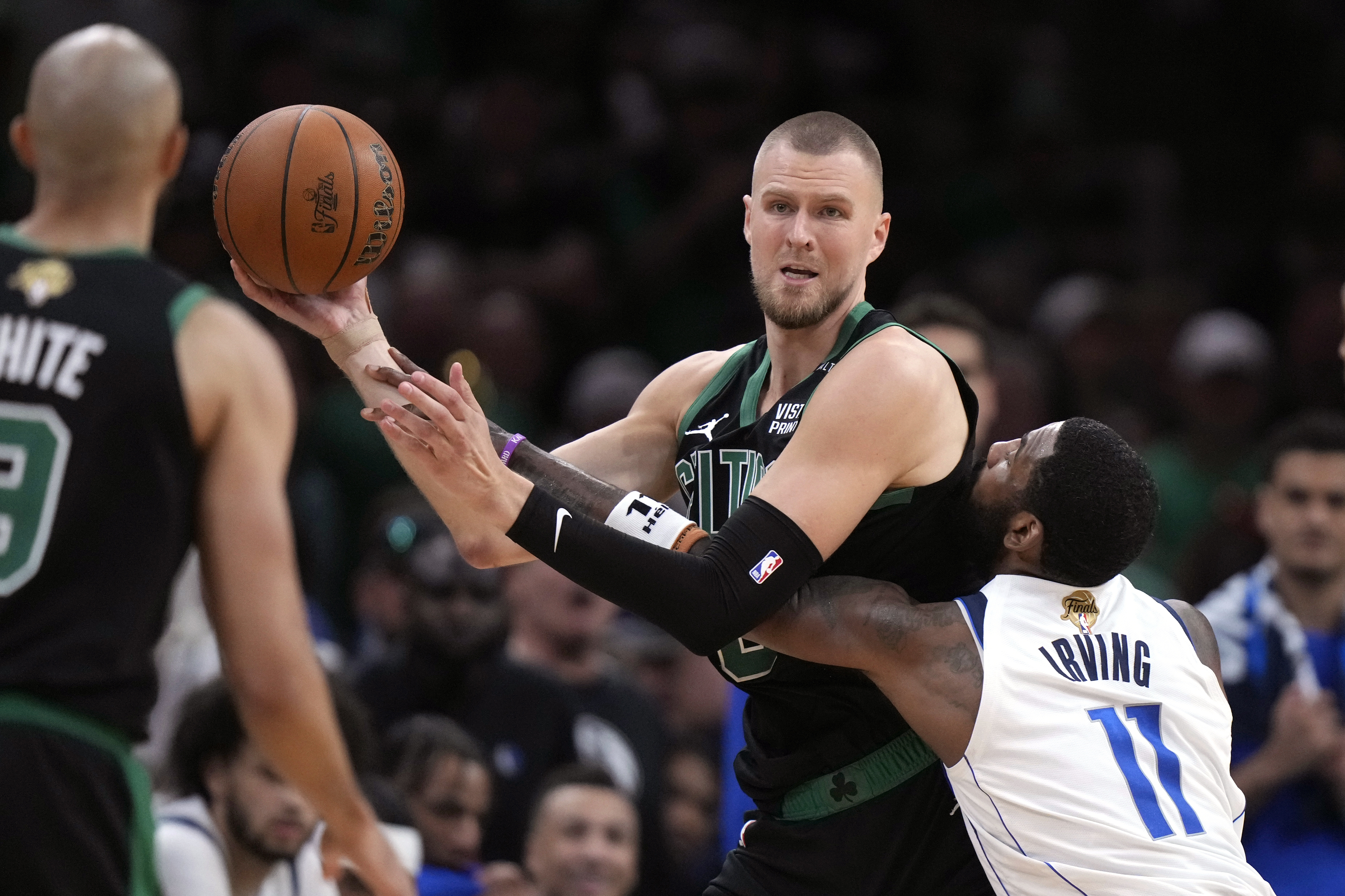 Boston Celtics center Kristaps Porzingis looks to pass while defended by Dallas Mavericks guard Kyrie Irving (11) during the second half of Game 2 of the NBA Finals basketball series, Sunday, June 9, 2024, in Boston. 