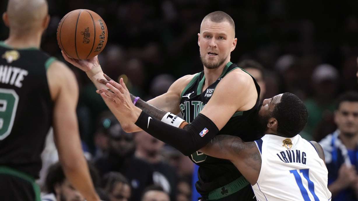 Boston Celtics center Kristaps Porzingis looks to pass while defended by Dallas Mavericks guard Kyrie Irving (11) during the second half of Game 2 of the NBA Finals basketball series, Sunday, June 9, 2024, in Boston.