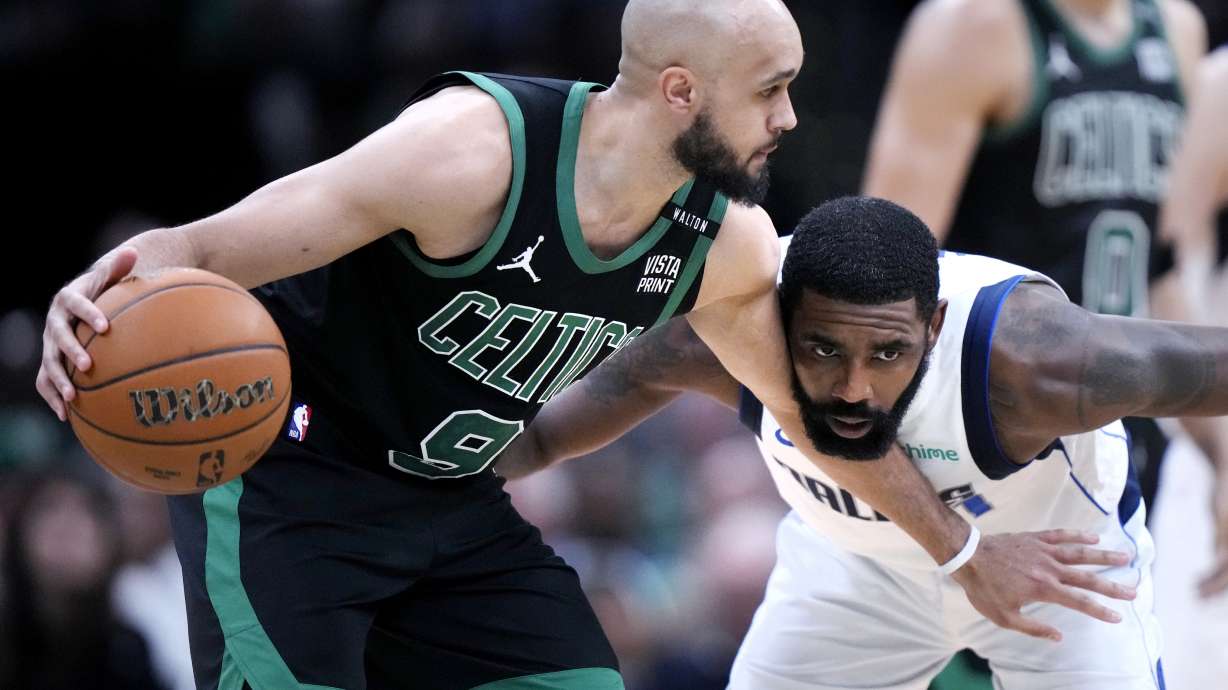 Boston Celtics guard Derrick White (9) holds back Dallas Mavericks guard Kyrie Irving while looking to pass during the second half of Game 2 of the NBA Finals basketball series, Sunday, June 9, 2024, in Boston.