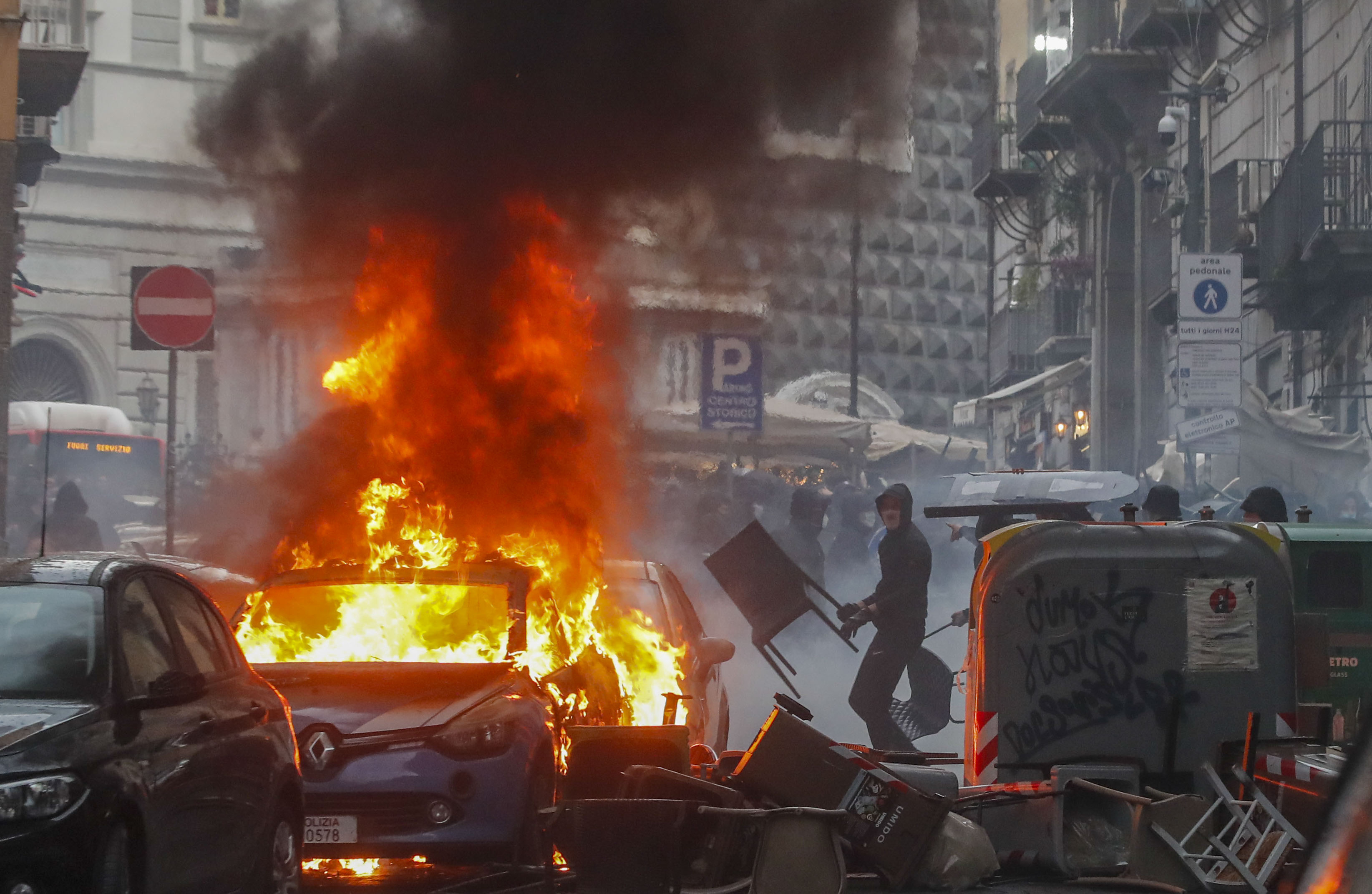 FILE - Supporters of the Eintracht Frankfurt soccer team set a police car afire as they clash with police in Naples, southern Italy, March 15, 2023, where their team is about to play a Champions League, round of 16, second leg soccer match against Naples. A recent surge in violence around soccer games is contributing to alarm over security when Germany hosts the European Championship. Some 22,000 police officers will be on duty each day for the tournament. 
