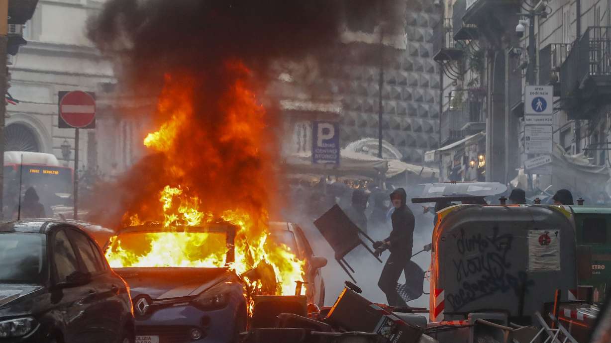 FILE - Supporters of the Eintracht Frankfurt soccer team set a police car afire as they clash with police in Naples, southern Italy, March 15, 2023, where their team is about to play a Champions League, round of 16, second leg soccer match against Naples. A recent surge in violence around soccer games is contributing to alarm over security when Germany hosts the European Championship. Some 22,000 police officers will be on duty each day for the tournament.