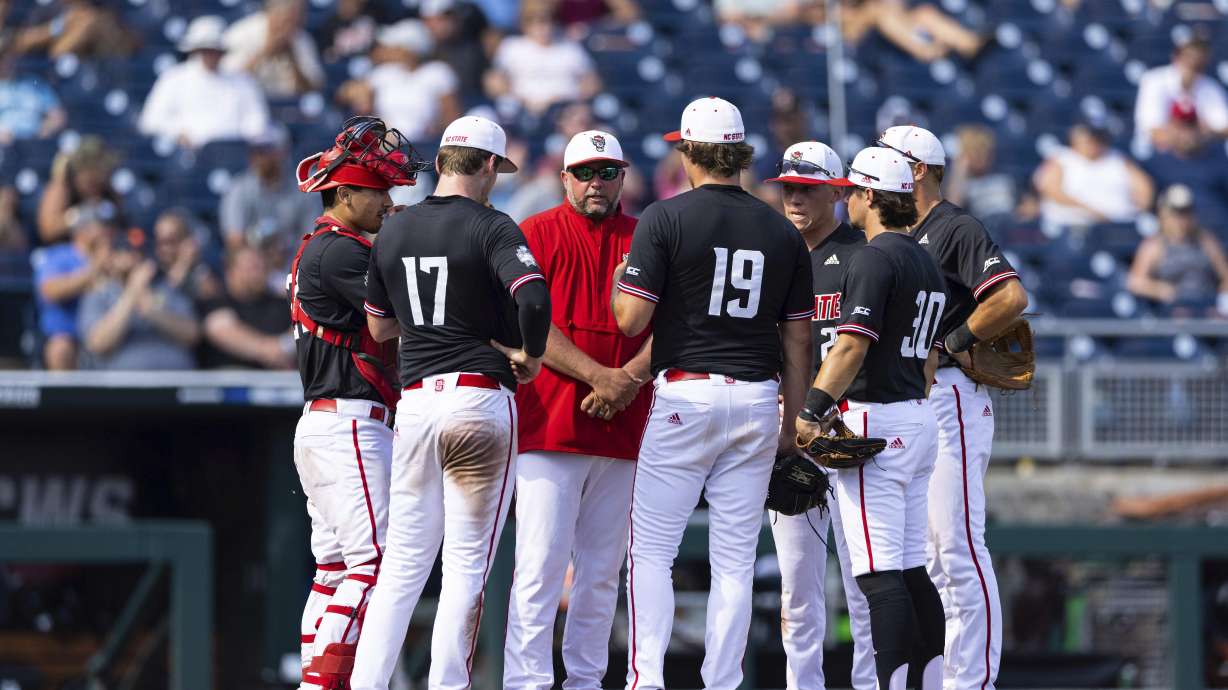 FILE - North Carolina State pitching coach Clint Chrysler, third from left, speaks with pitcher Dalton Feeney (19) during a meeting on the mound in the eighth inning against Vanderbilt during a baseball game in the College World Series Friday, June 25, 2021, at TD Ameritrade Park in Omaha, Neb. No return trip to the College World Series was ever promised when the 2021 Wolfpack were sent home by the NCAA amid a COVID-19 outbreak on the team. Four players from that team have made it back, and they're savoring every moment. The Wolfpack play Kentucky in their opener Saturday.