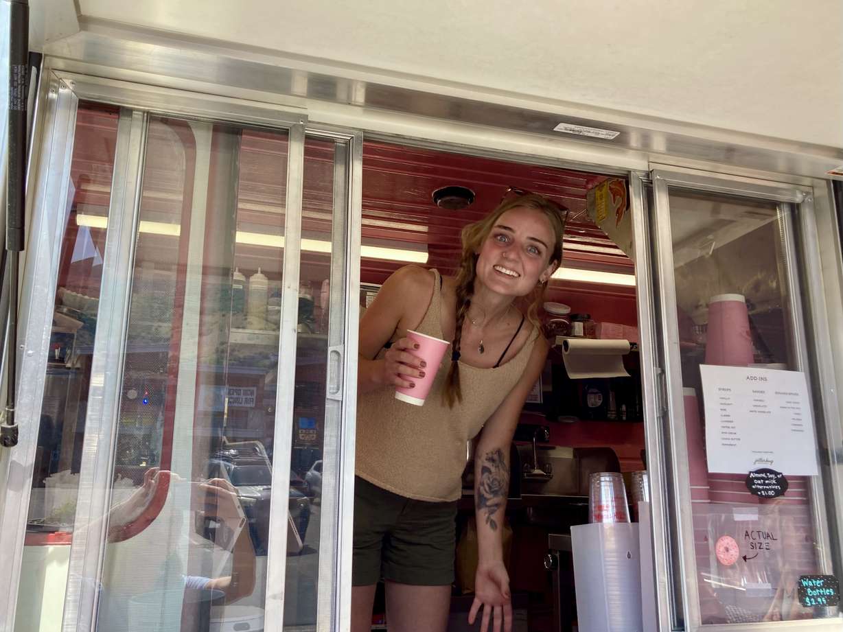 Manager Emma Beerman works inside of Jitterbug Coffee's pink truck. Most of the space in the truck is occupied by the doughnut fryer.