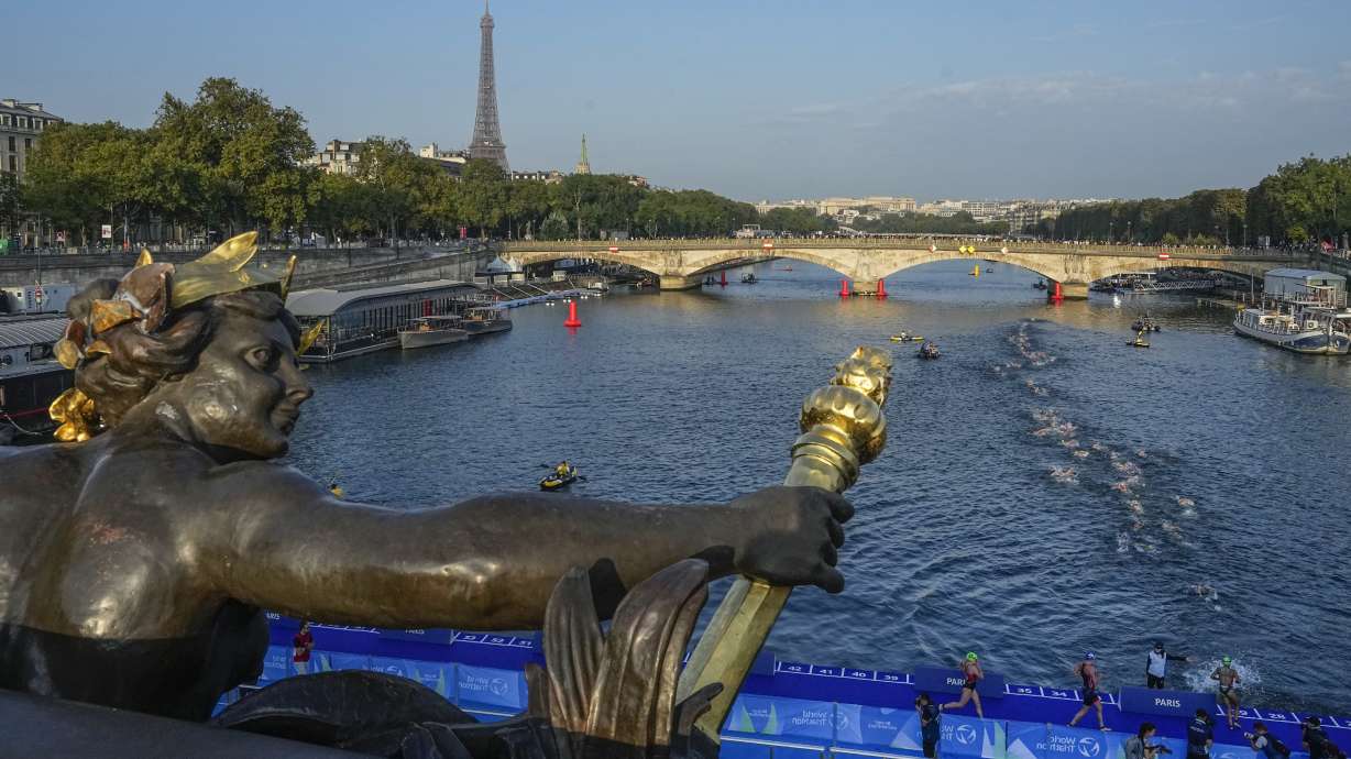 FILE - Athletes dive and swim in the Seine River from the Alexander III bridge on the first leg of the women's triathlon test event for the Olympics Games in Paris, Aug. 17, 2023. Water in the Seine River had unsafe elevated levels of E. coli less than two months before swimming competitions are scheduled to take place in it during the Paris Olympics, according to test results published Friday, June 14, 2024.