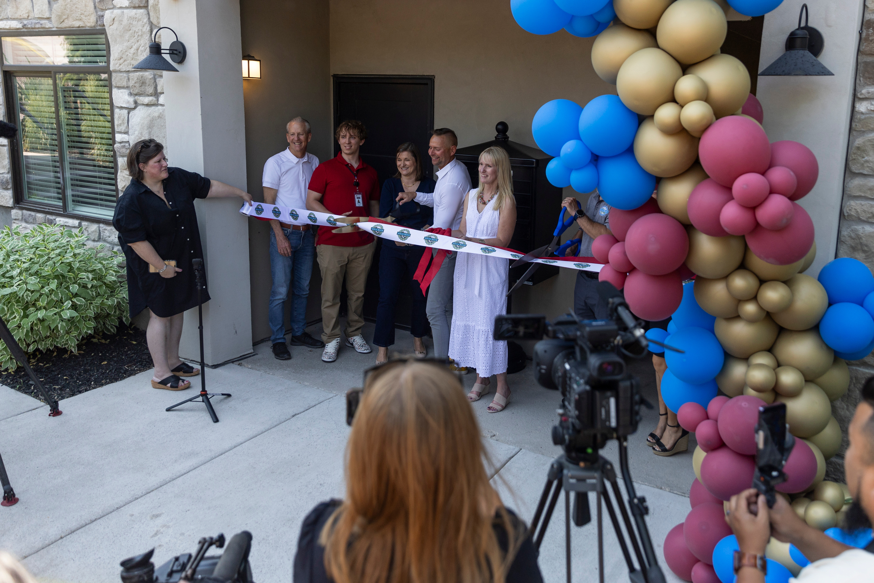 A ribbon is cut led by Rotary Club President-Elect Spencer Ferguson and Salt Lake County Mayor Jenny Wilson in celebration during the grand opening of the Salt Lake County Youth Services Milestone transitional living building in Millcreek on Friday.