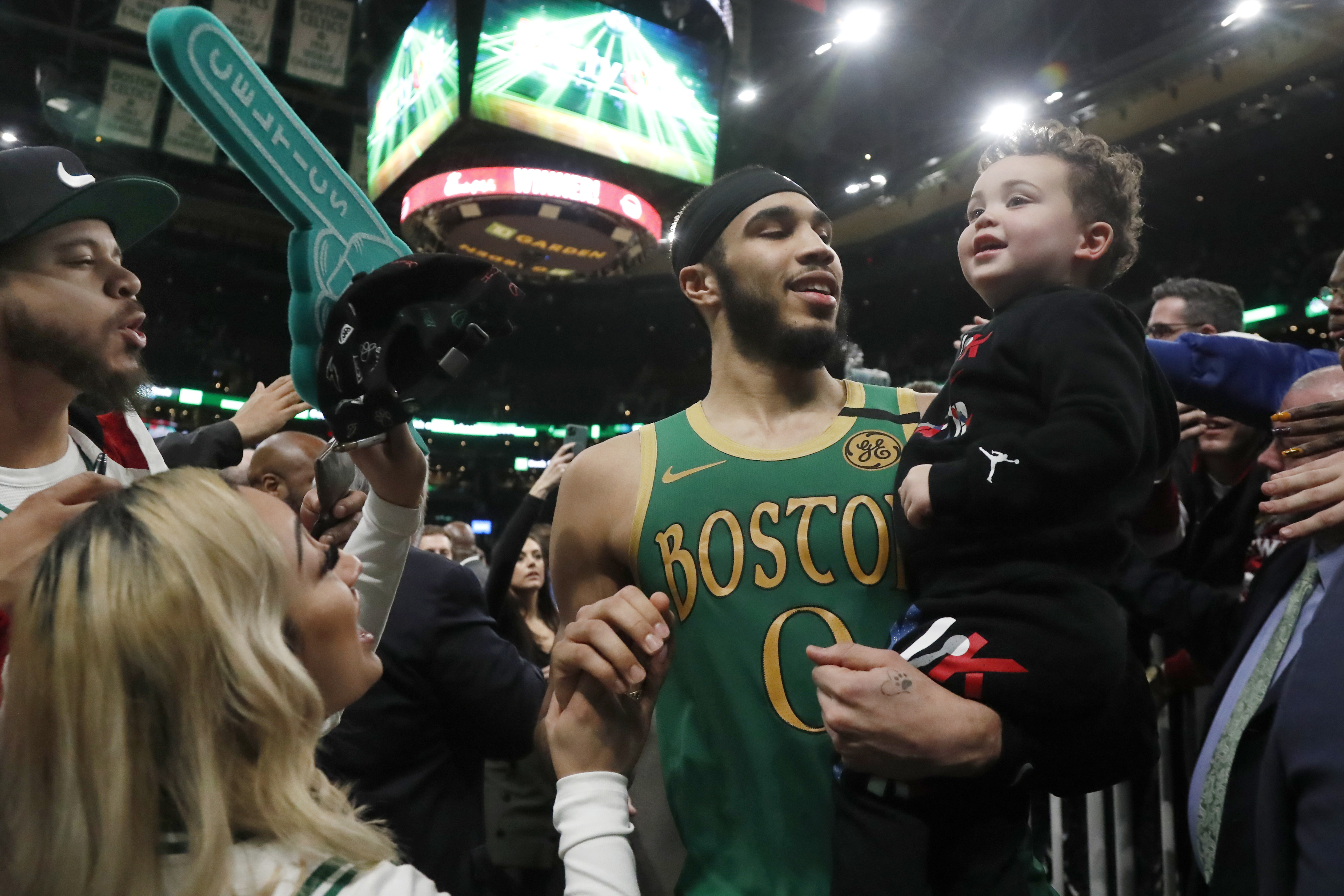 FILE - Fans reach out to Boston Celtics forward Jayson Tatum (0) as he leaves the court holding his son, Deuce, after the Celtics defeated the Los Angeles Clippers in a double overtime NBA basketball game, Feb. 13, 2020, in Boston. Tatum spent part of his Father’s Day, Sunday, June 16, 2024, thinking about how his son made him a better person — and probably a better basketball player, too.
