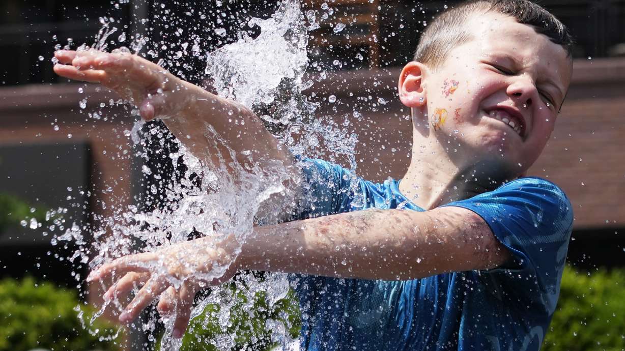 A boy cools off at a fountain outside Wrigley Field before a baseball game between the Chicago Cubs and St. Louis Cardinals as hot weather descends upon the Chicago area Sunday.