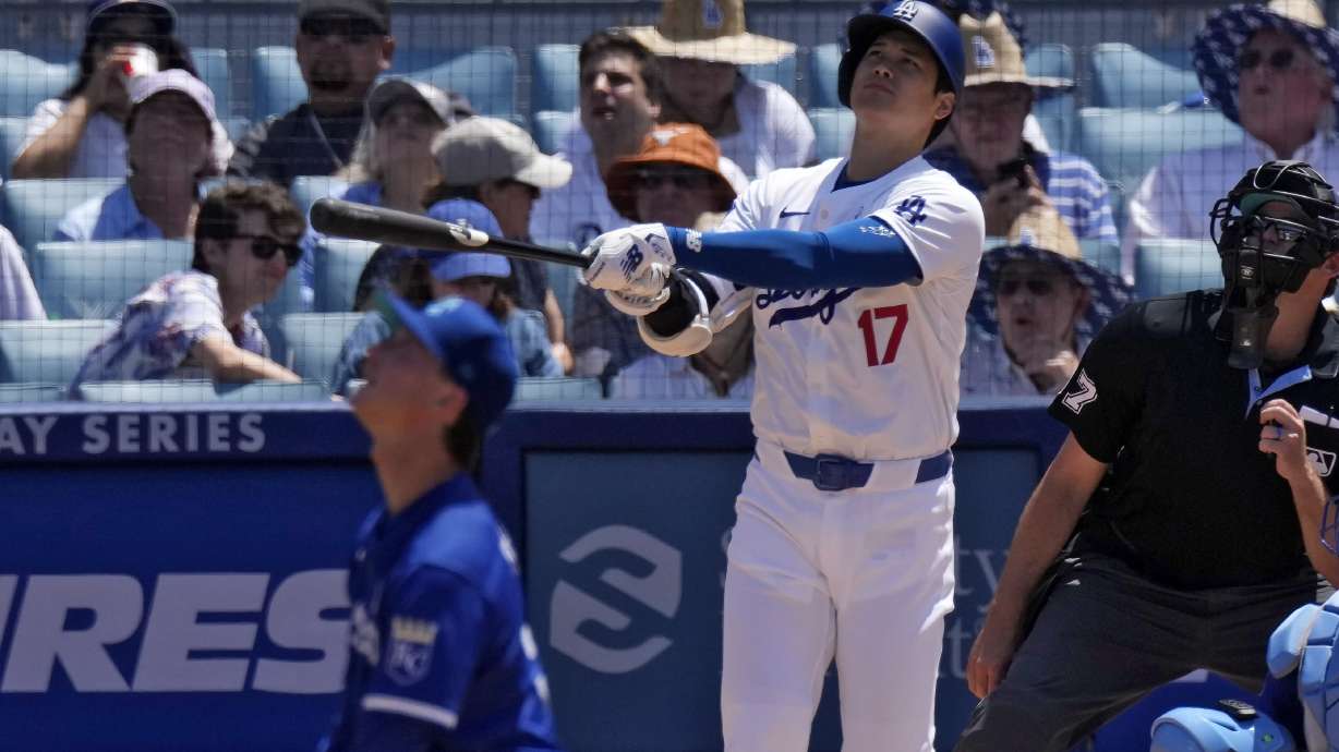 Los Angeles Dodgers' Shohei Ohtani, center, hits a solo home run as Kansas City Royals starting pitcher Brady Singer, left, and home plate umpire Ryan Additon watch during the sixth inning of a baseball game Sunday, June 16, 2024, in Los Angeles.