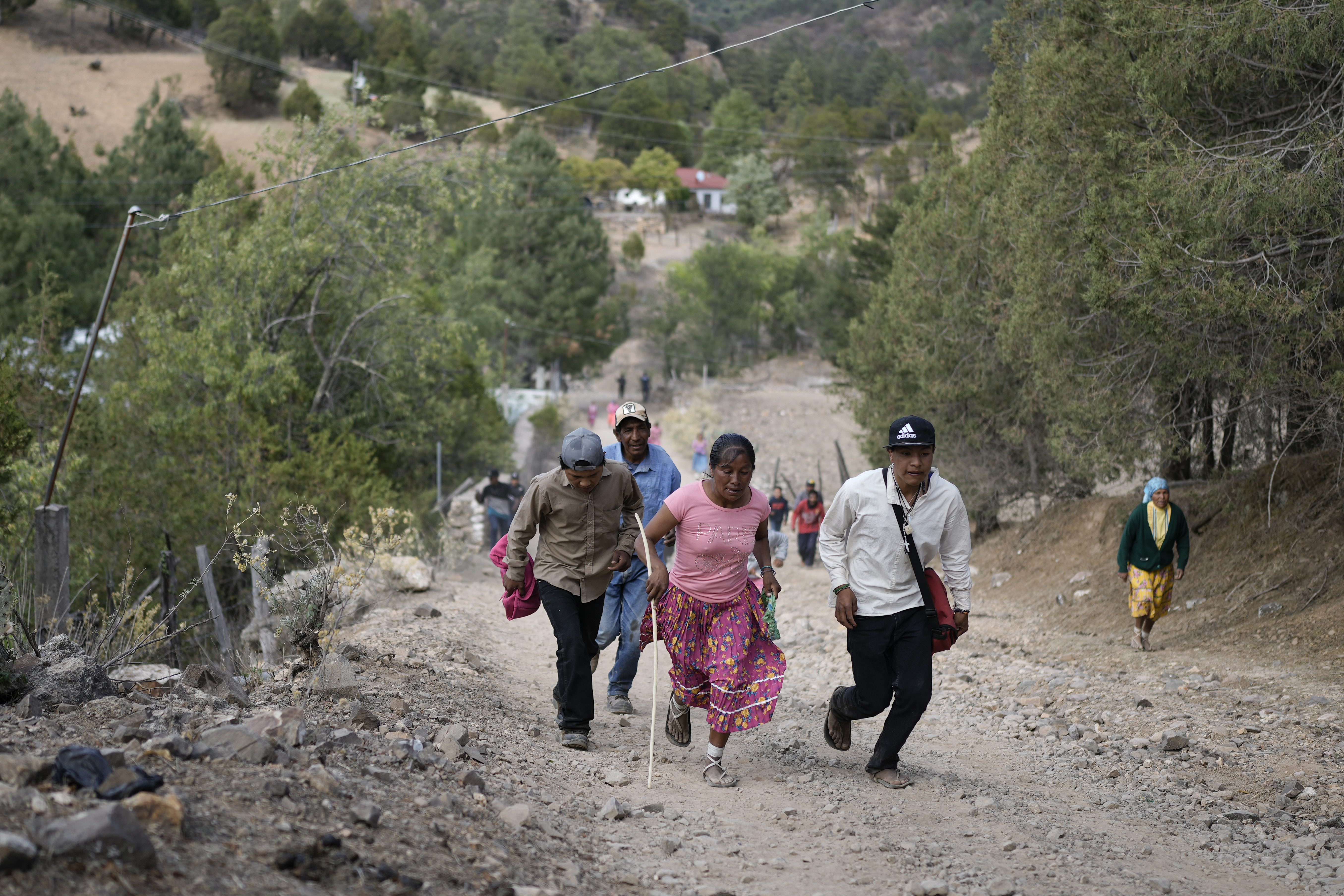Rarámuri runner Teresa Sánchez is accompanied by residents as she competes in the Arihueta race in Cuiteco, Mexico, Saturday, May 11, 2024. “I always run in sandals,” Sánchez said. “I wear them every day and they last up to 2 or 3 years.