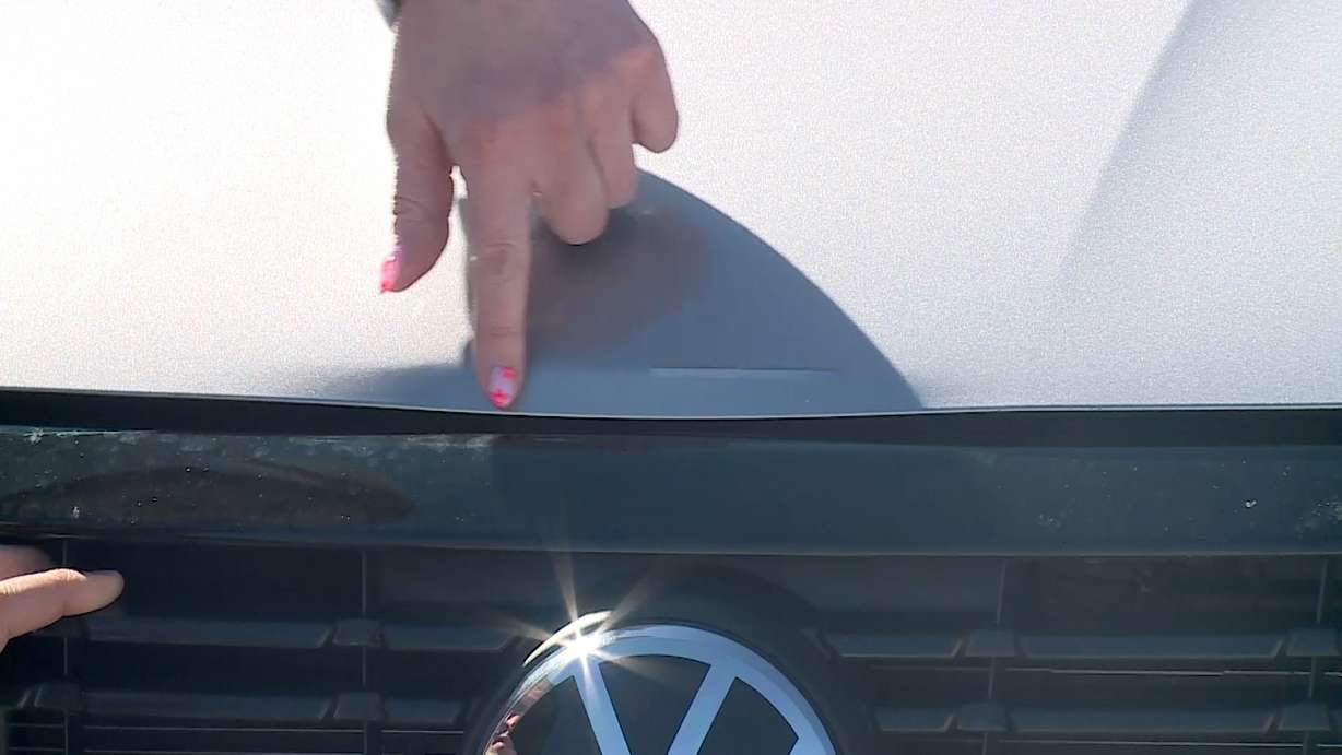 Lynzee Delapaz points to the damage on her car caused by the collision inside the car wash in this undated image.