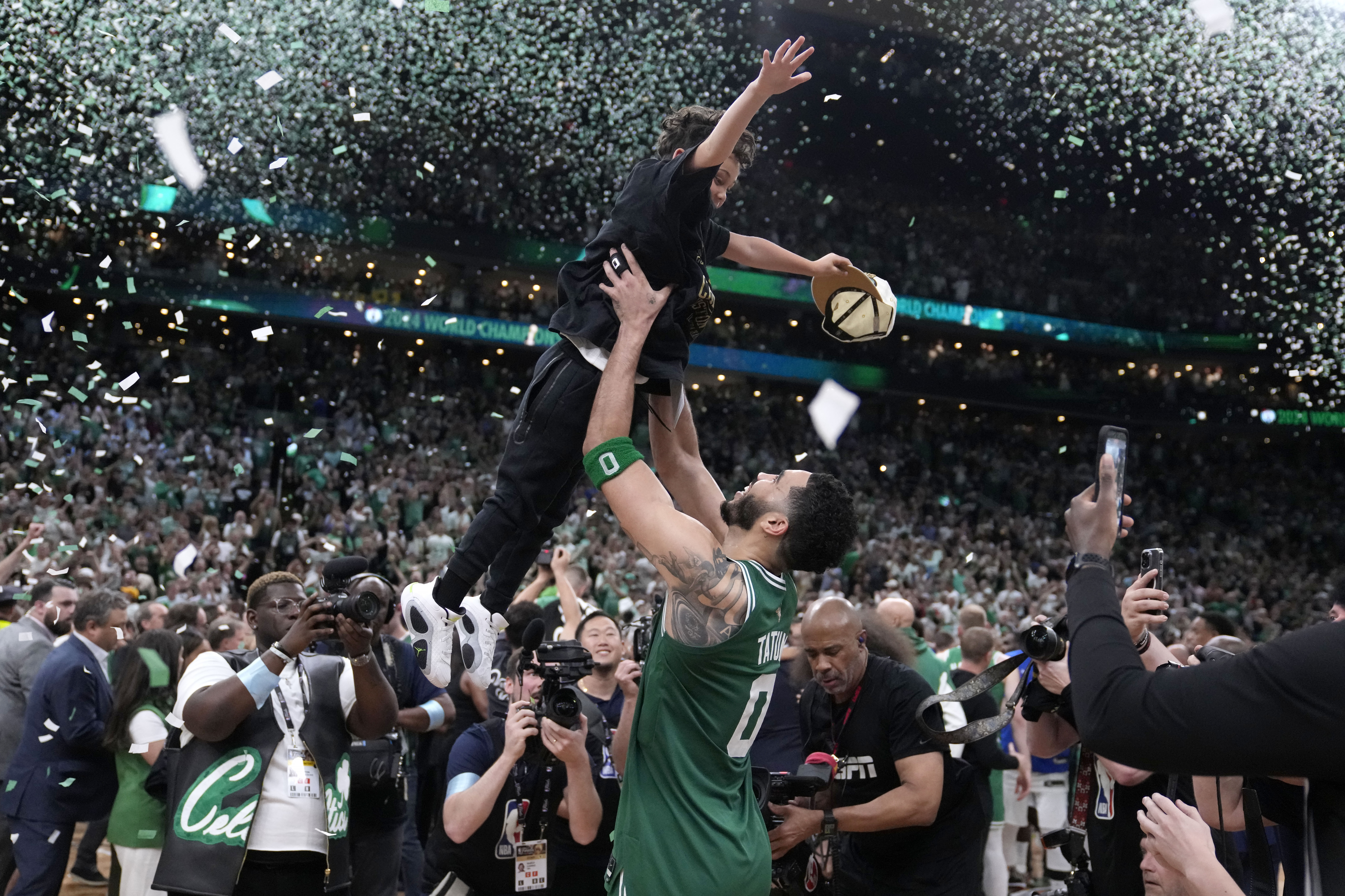 Boston Celtics forward Jayson Tatum (0) lifts his son Deuce as he celebrates with the team after the Celtics won the NBA basketball championship with a Game 5 victory over Dallas Mavericks, Monday, June 17, 2024, in Boston. 