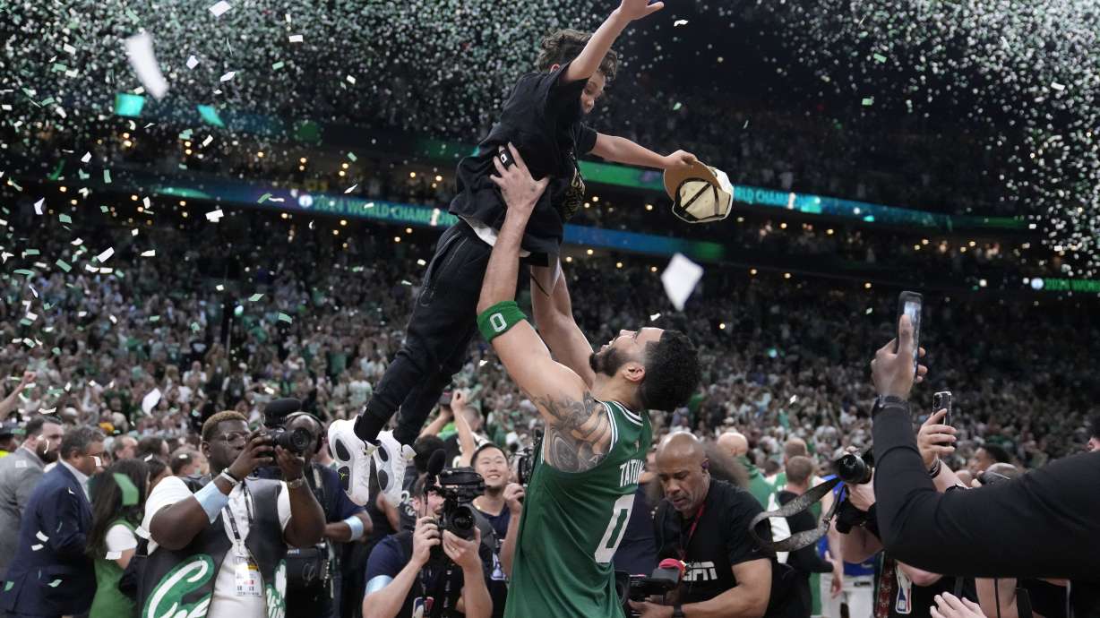 Boston Celtics forward Jayson Tatum (0) lifts his son Deuce as he celebrates with the team after the Celtics won the NBA basketball championship with a Game 5 victory over Dallas Mavericks, Monday, June 17, 2024, in Boston.