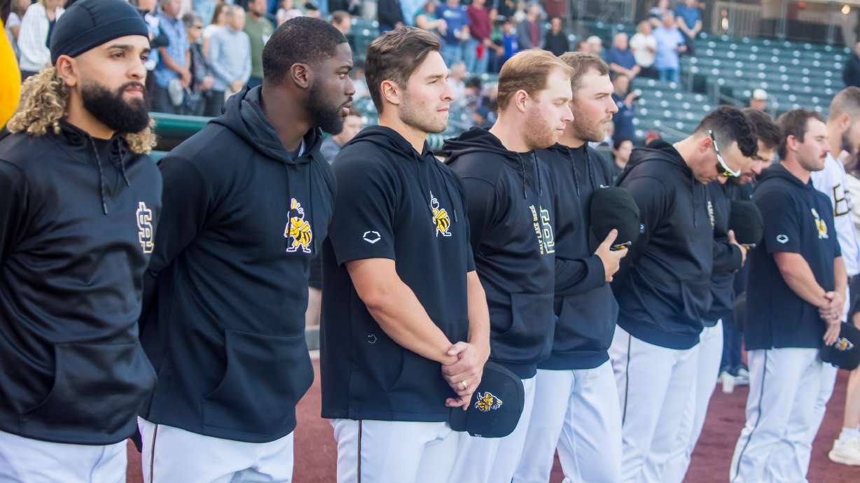 Salt Lake Bees players bow their heads during a moment of silence for longtime Bees broadcaster Steve Klauke before the team's game against the Reno Aces at Smith's Ballpark on Tuesday. Tuesday's game was the first Bees home game after Klauke's death last week.