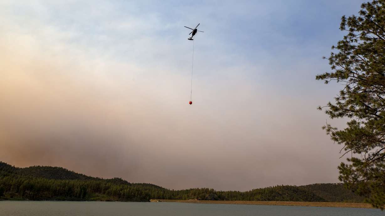 A helicopter collects water from Mescalero lake near the Inn of the Mountain Gods Resort in Ruidoso, N.M., as authorities fight wildfires Tuesday. Thousands of residents fled their homes as a wildfire swept into a New Mexico town.