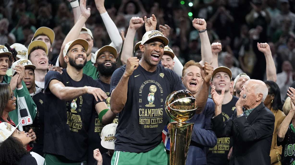 Boston Celtics center Al Horford, center, and forward Jayson Tatum, front center left, celebrate with teammates near the Larry O'Brien Championship Trophy after winning the NBA championship with a Game 5 victory over the Dallas Mavericks on Monday, June 17, 2024, in Boston.