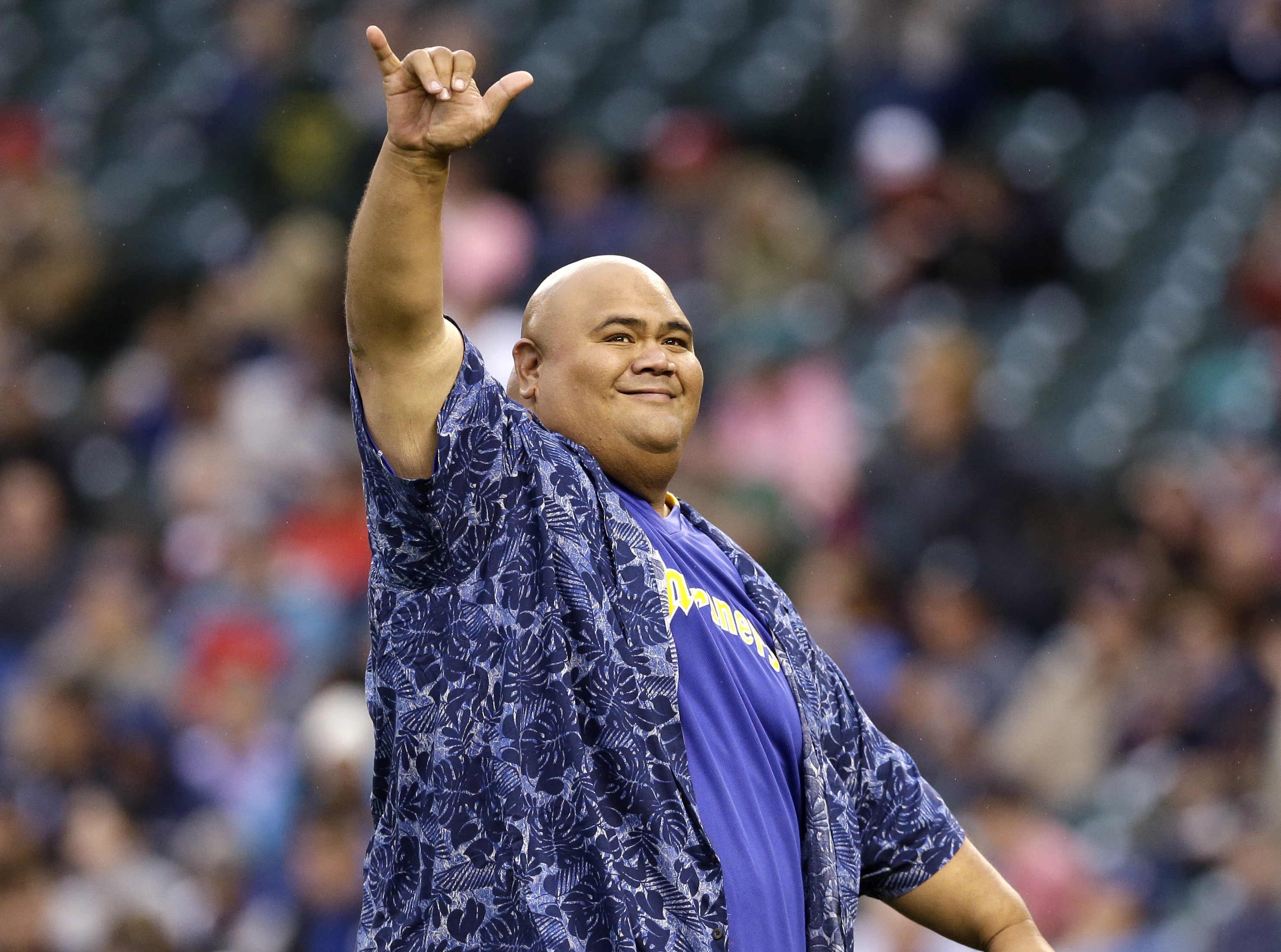 FILE - Actor Taylor Wily, also known as Teila Tuli, of "Hawaii Five-0," gestures to fans after throwing out the ceremonial first pitch before a baseball game between the Seattle Mariners and Texas Rangers in Seattle on June 14, 2014.