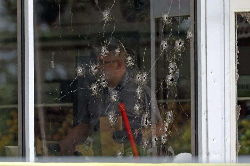 Damage can be seen to a front window law enforcement officers work the scene of a shooting at the Mad Butcher grocery store in Fordyce, Ark., Friday.