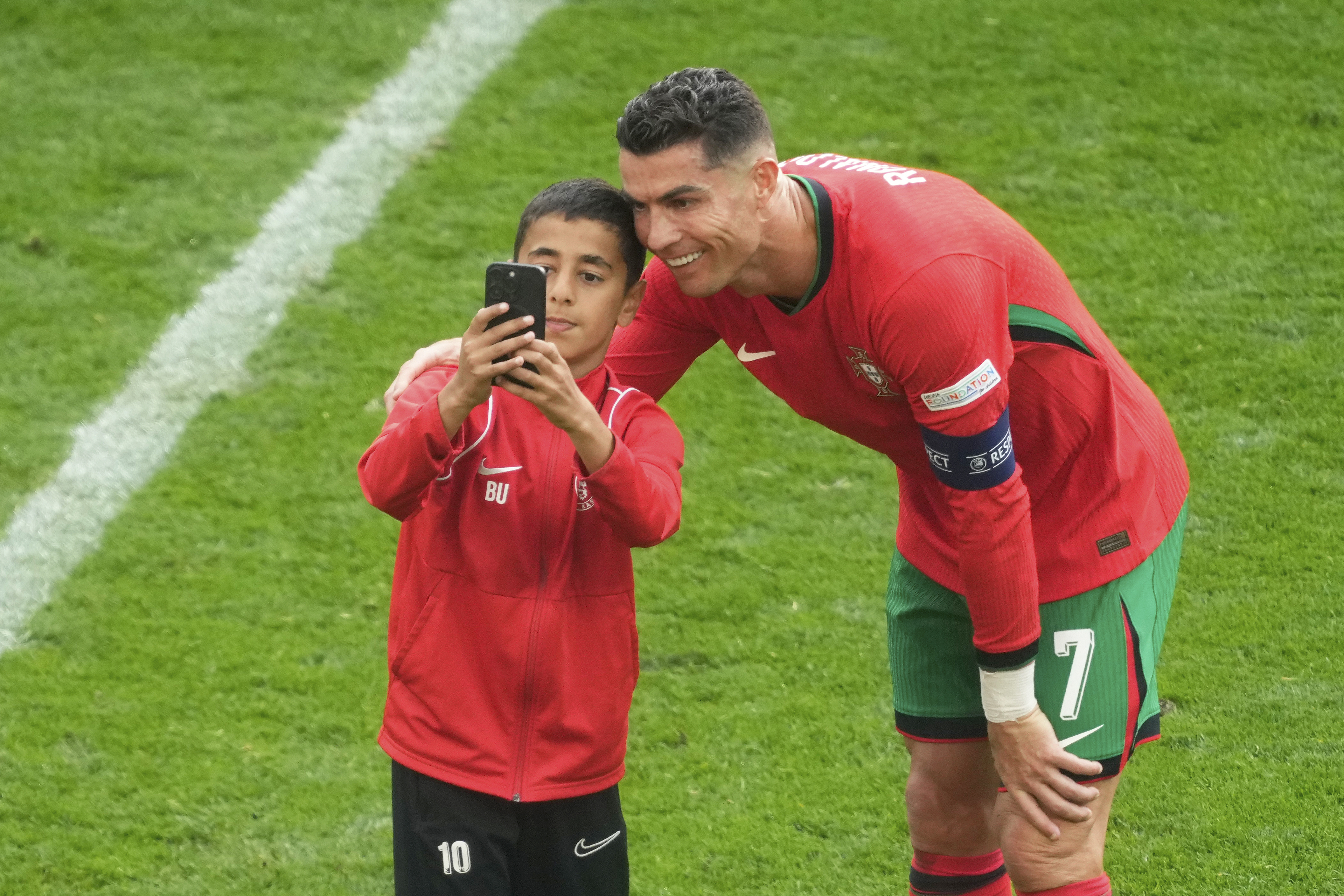 A young pitch invader takes a selfie with Portugal's Cristiano Ronaldo during a Group F match between Turkey and Portugal at the Euro 2024 soccer tournament in Dortmund, Germany, Saturday, June 22, 2024.