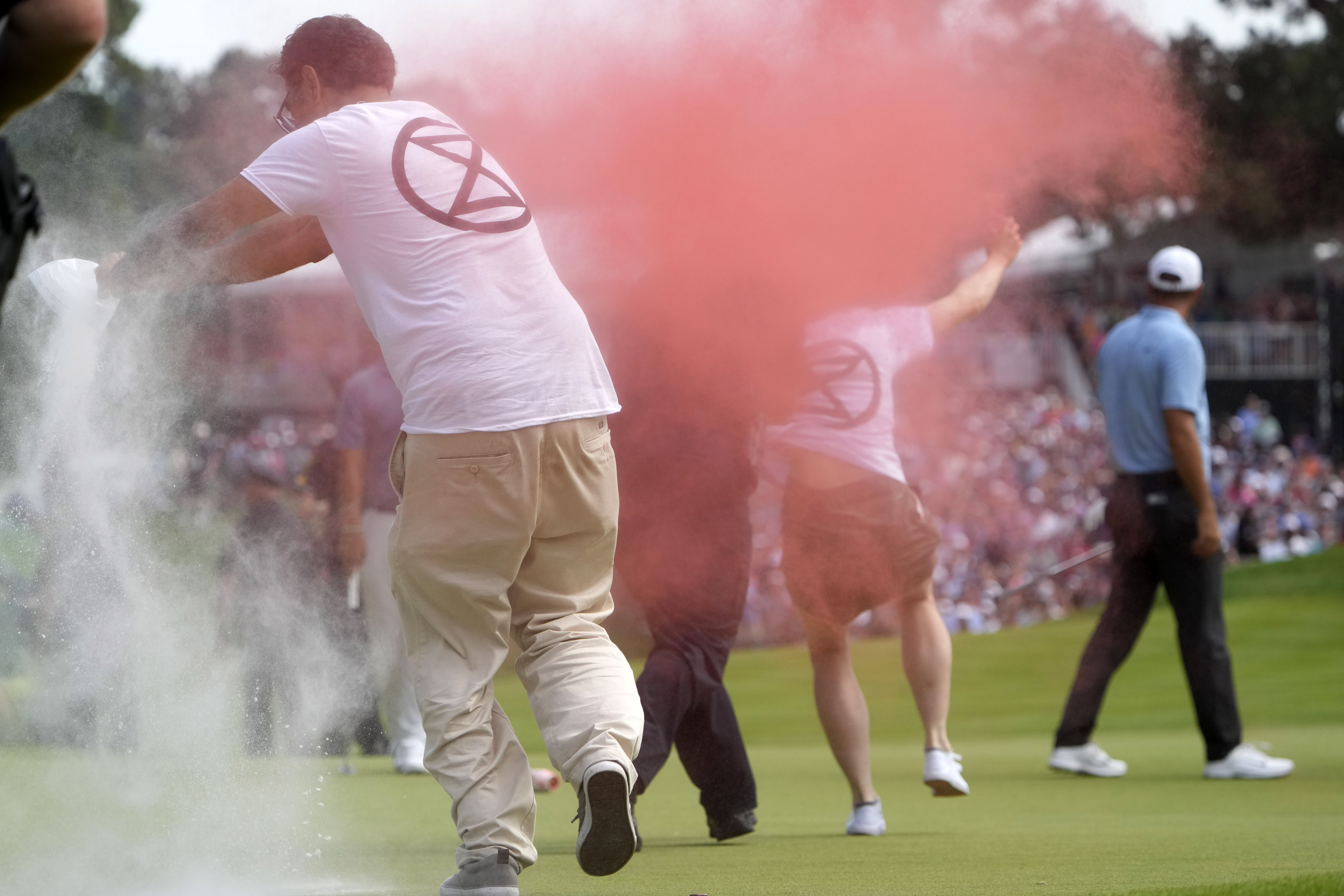Protesters run onto the course as Scottie Scheffler, right, walks away on the 18th hole during the final round of the Travelers Championship golf tournament at TPC River Highlands, Sunday, June 23, 2024, in Cromwell, Conn.