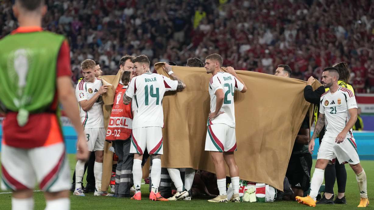 Players hold a blanket as medical personnel treat Hungary's Barnabas Varga during a Group A match between Scotland and Hungary at the Euro 2024 soccer tournament in Stuttgart, Germany, Sunday, June 23, 2024.