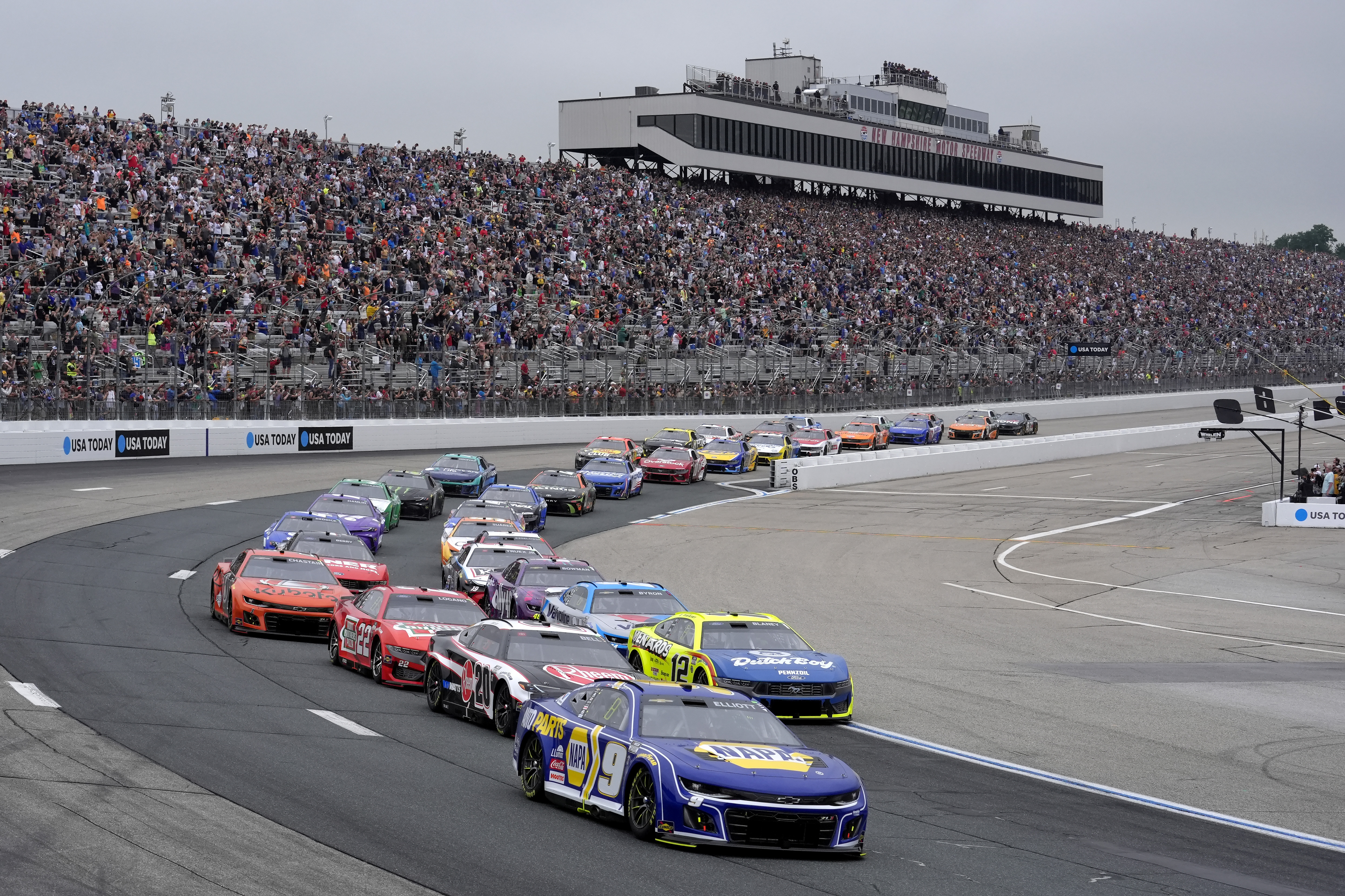 Chase Elliott (9) steers his car while leading a tight pack as they enter Turn 2 during a NASCAR Cup Series race, Sunday, June 23, 2024, at New Hampshire Motor Speedway, in Loudon, N.H.