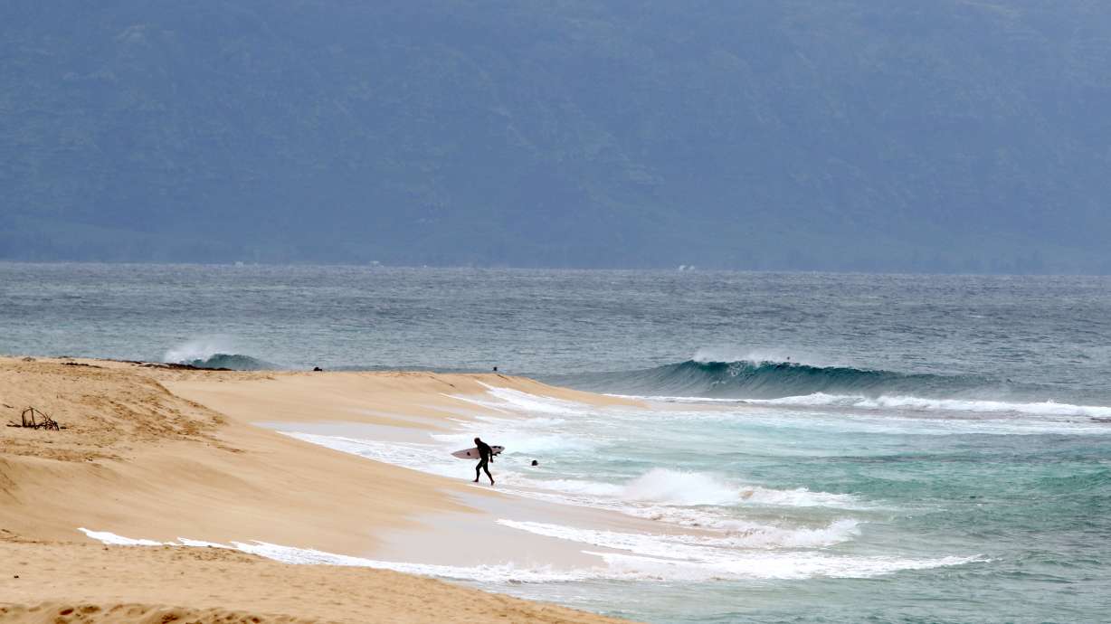 FILE - A surfer walks out of the ocean on Oahu's North Shore near Haleiwa, Hawaii, March 31, 2020. Authorities said a professional lifeguard died after he was attacked by a shark while surfing off the island of Oahu in Hawaii on Sunday afternoon, June 23, 2024.